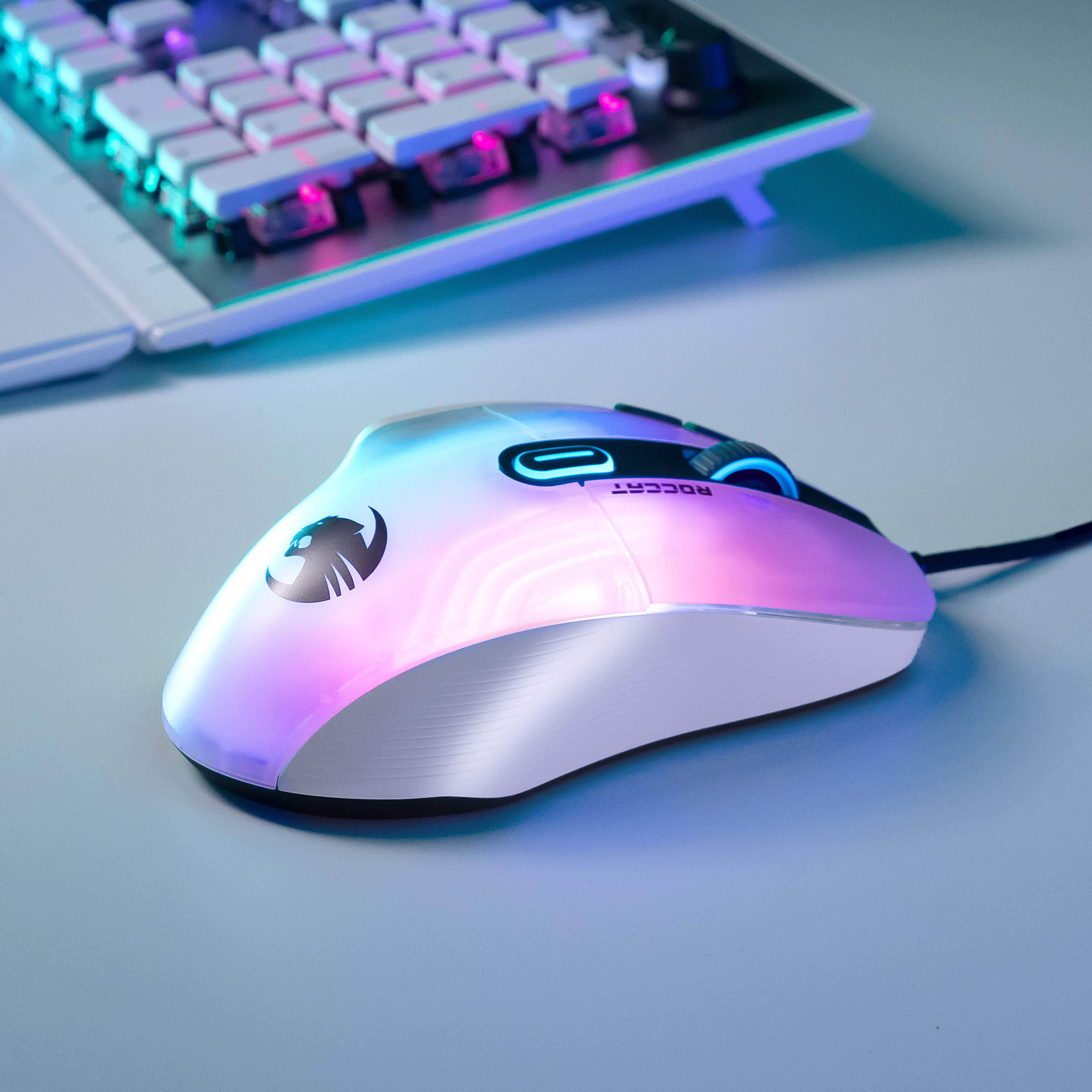 Gaming-Maus mit RGB-Beleuchtung, Tastatur im Hintergrund. Die Maus hat ein Logo.
