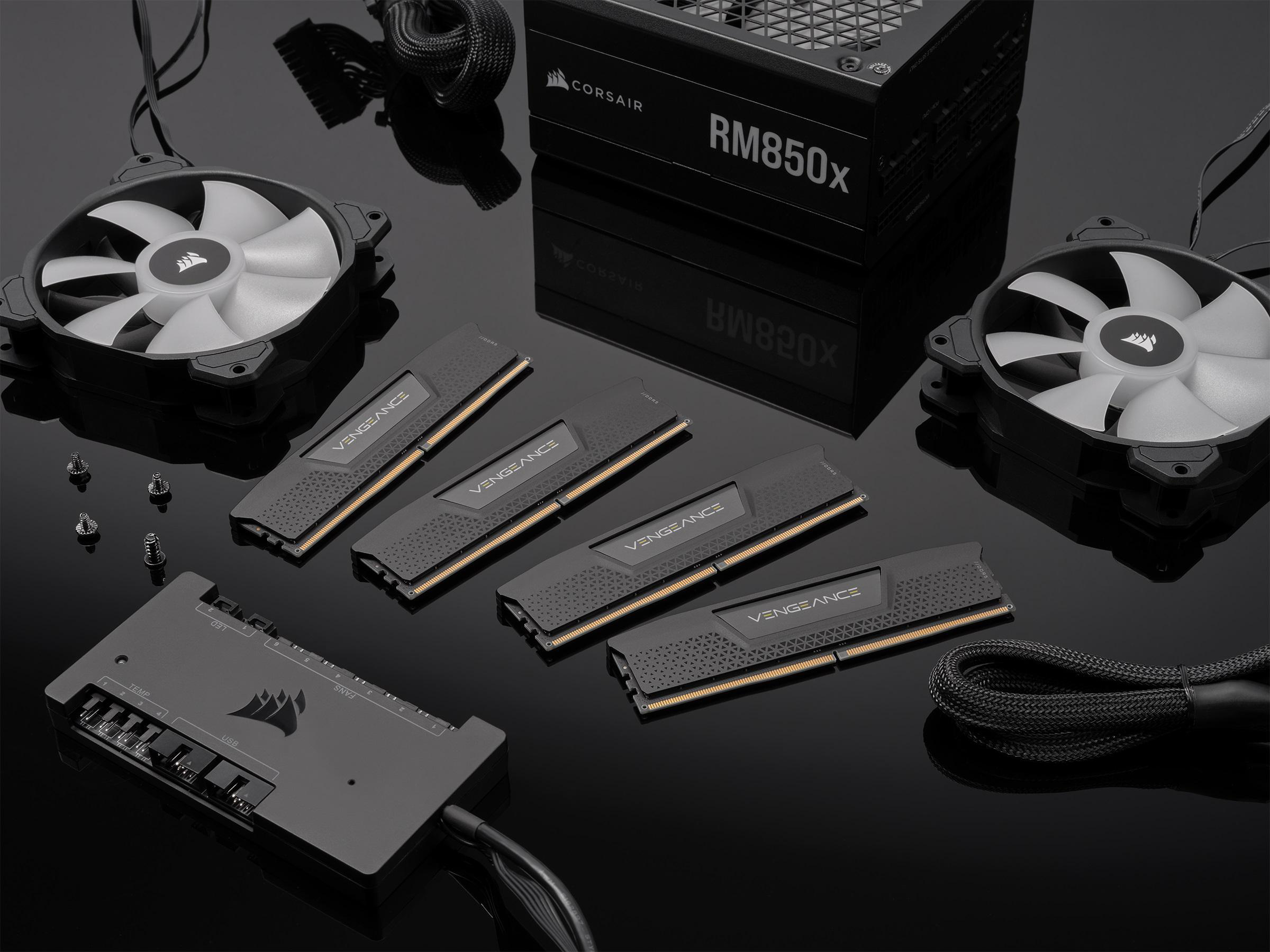Computerkomponenten: Corsair-Netzteil, RAM-Module, Lüfter und ein Controller auf schwarzer Oberfläche.