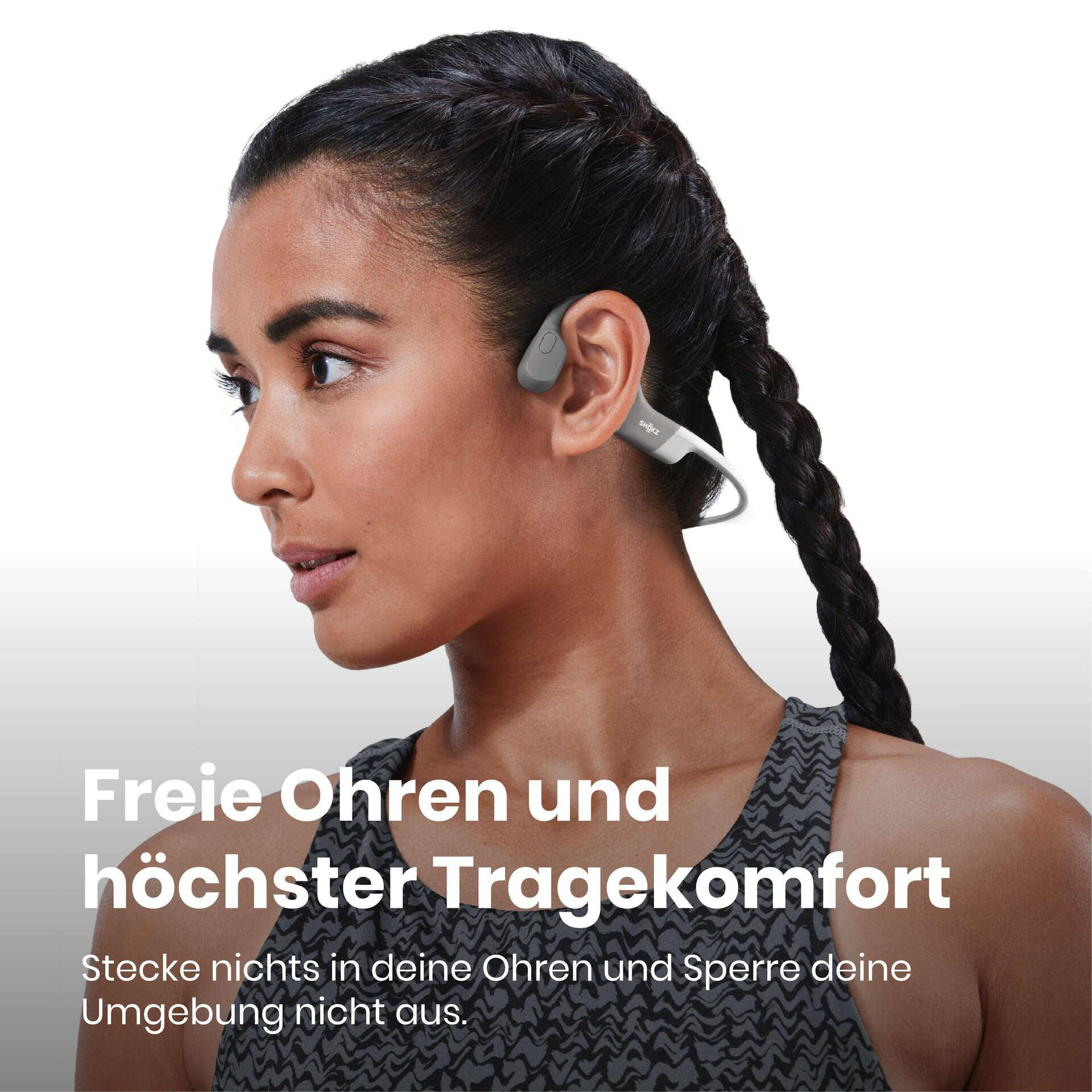 Eine Frau mit Kopfhörern. Sie hat dunkle Haare, ein graues Top und der Text auf Deutsch lautet 'Freie Ohren und höchster Komfort'.