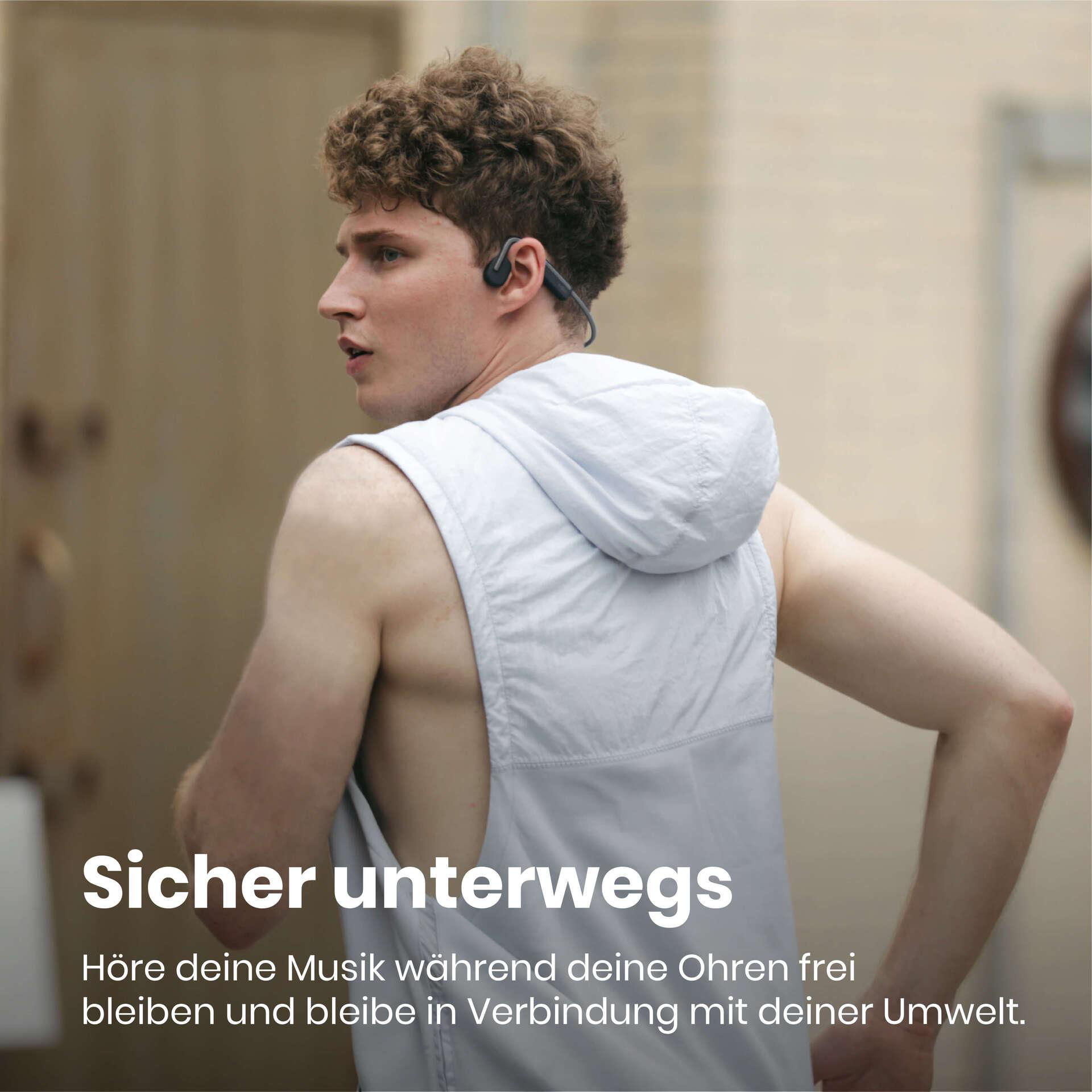 Ein Mann mit weißer Weste und Kopfhörern beim Laufen. Der Hintergrund ist verschwommen und beige.