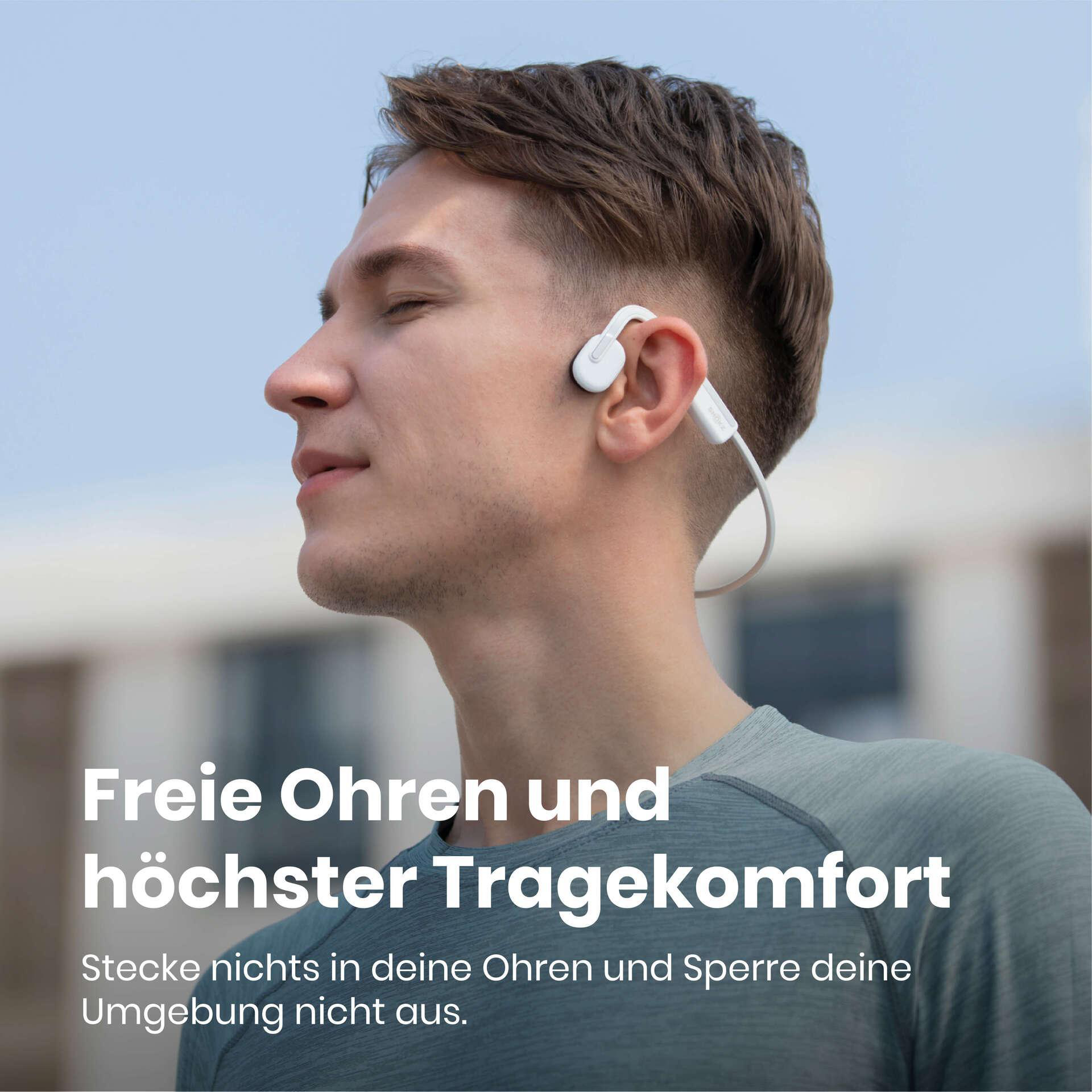 Ein Mann trägt weiße Open-Ear-Kopfhörer. Er schaut mit geschlossenen Augen zur Seite. Text: Freie Ohren und höchster Tragekomfort.