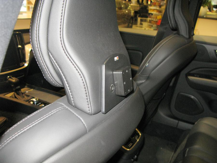 Appuie-tête de siège auto avec un support rectangulaire noir. Le siège est en cuir noir avec des coutures blanches.