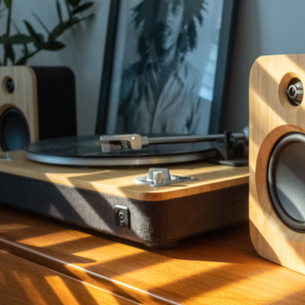 Een platenspeler met speakers op houten meubels, een ingelijste foto op de achtergrond.