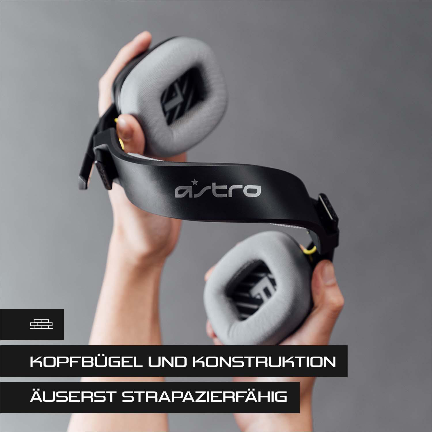 Person hält Headset, schwarzer Rahmen mit grauen Ohrmuscheln und Astro-Logo.