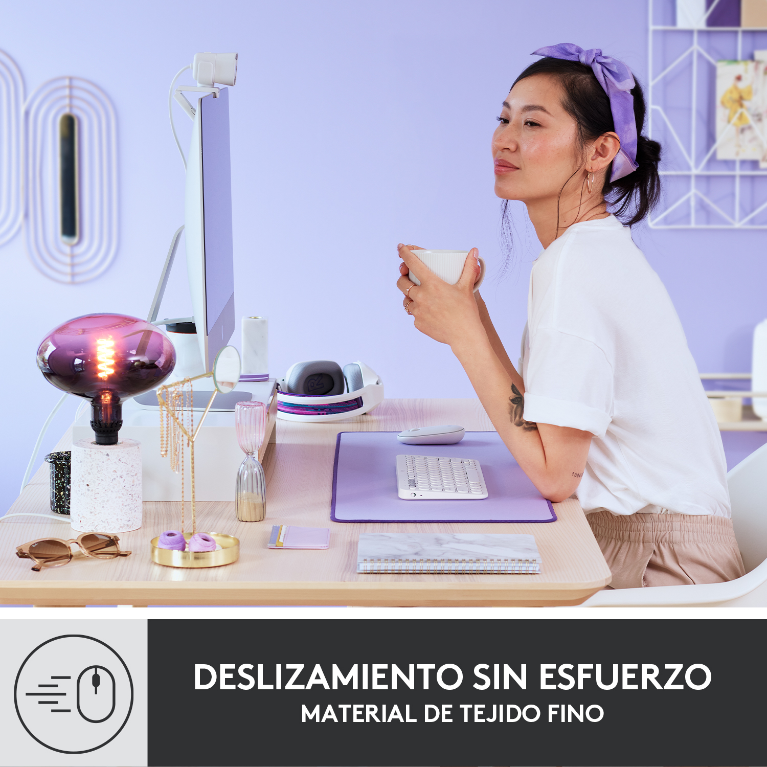 Una mujer trabajando en un escritorio con una computadora. Hay una alfombrilla de escritorio morada, un teclado y un mouse. Texto en la parte inferior.