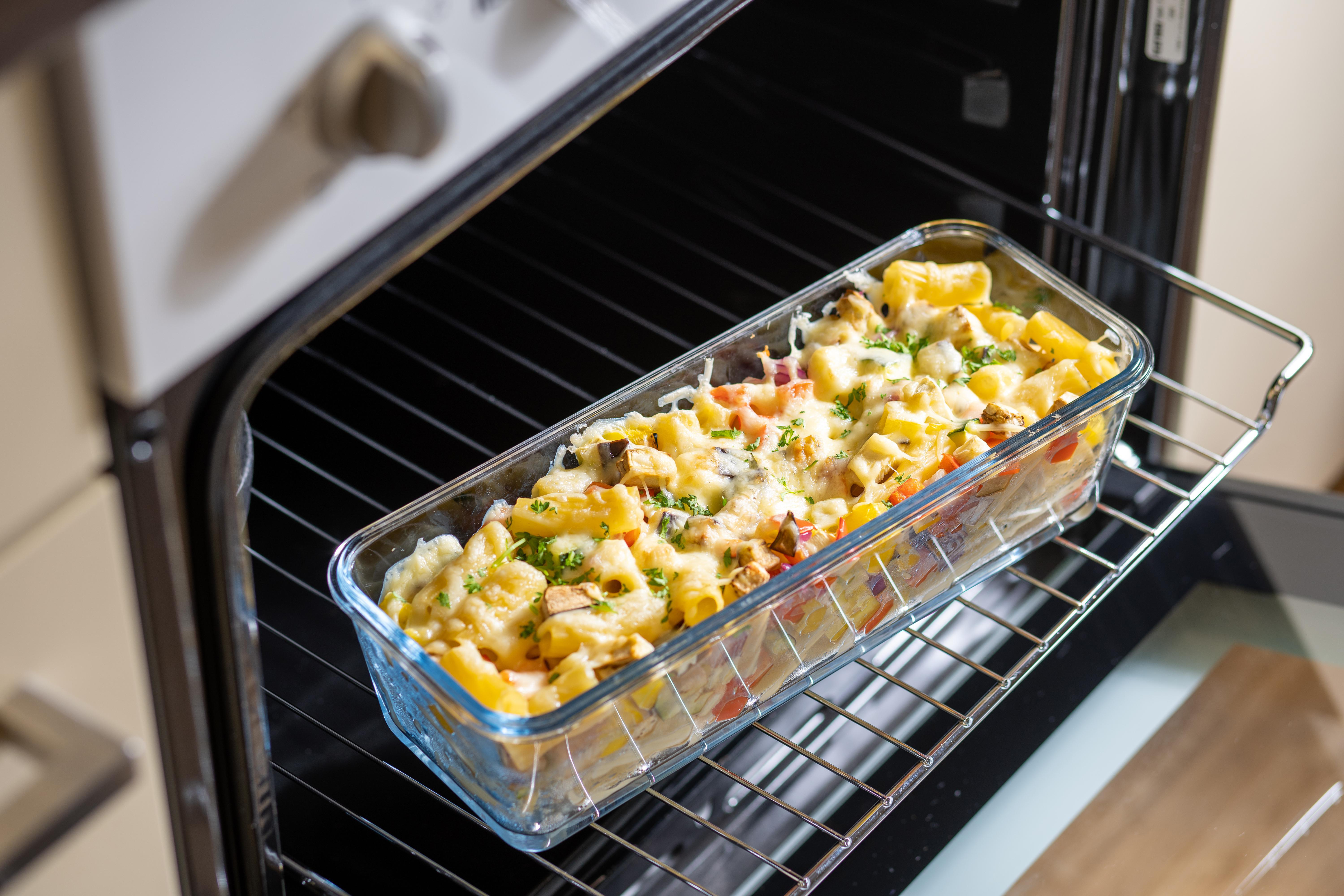 Pastagericht im Ofen. Glas-Backform mit gekochter Pasta, Käse und Gemüse.