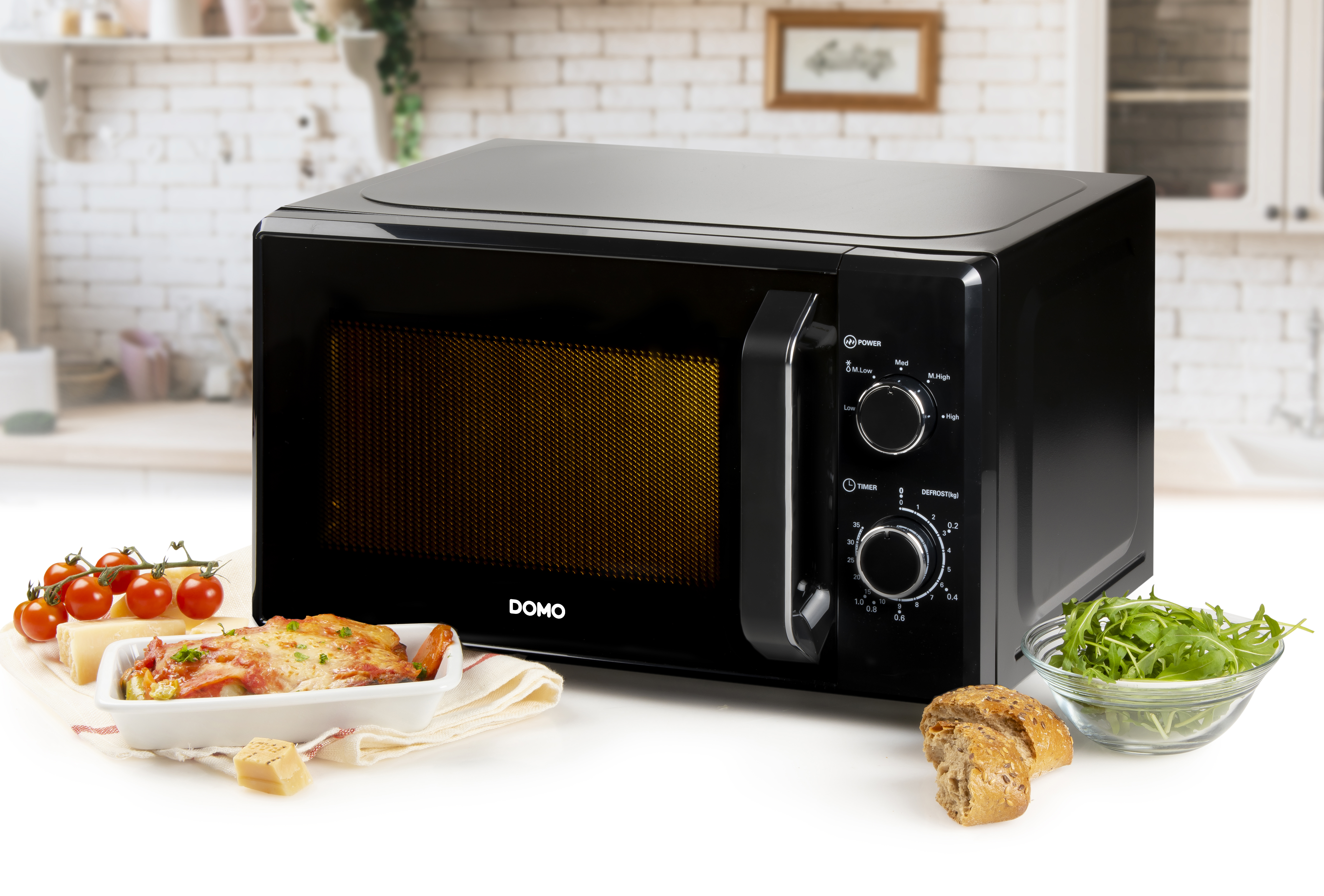 Black microwave on a kitchen counter, with food and ingredients. DOMO branding is visible.