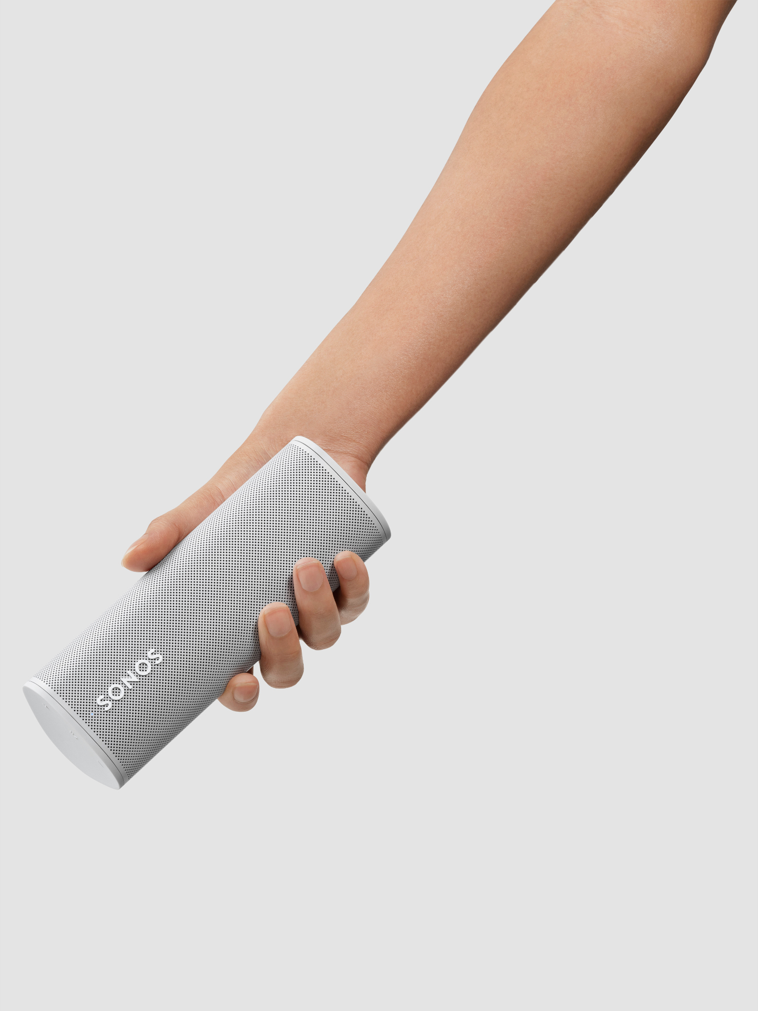 Een hand houdt een witte Sonos-luidspreker vast. De luidspreker is cilindrisch.