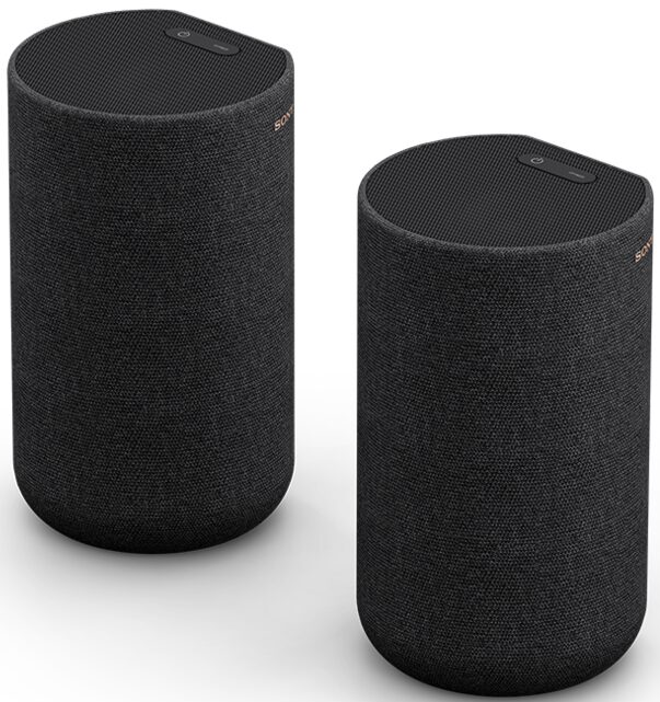 Deux enceintes cylindriques noires. Chacune a un bouton d'alimentation supérieur et une housse en tissu.