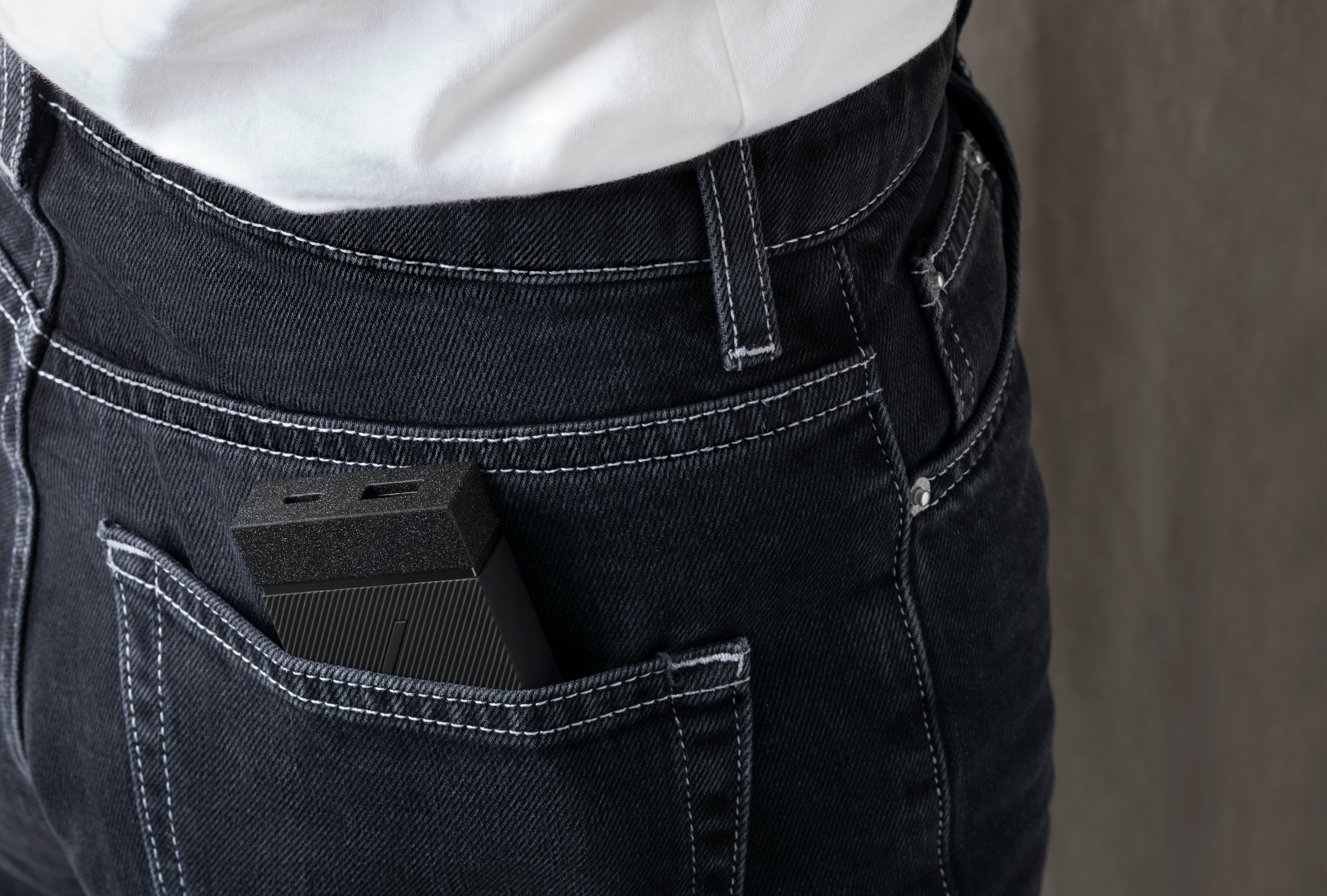 Una persona in jeans ha un dispositivo nero nella tasca posteriore. La tasca è visibile.