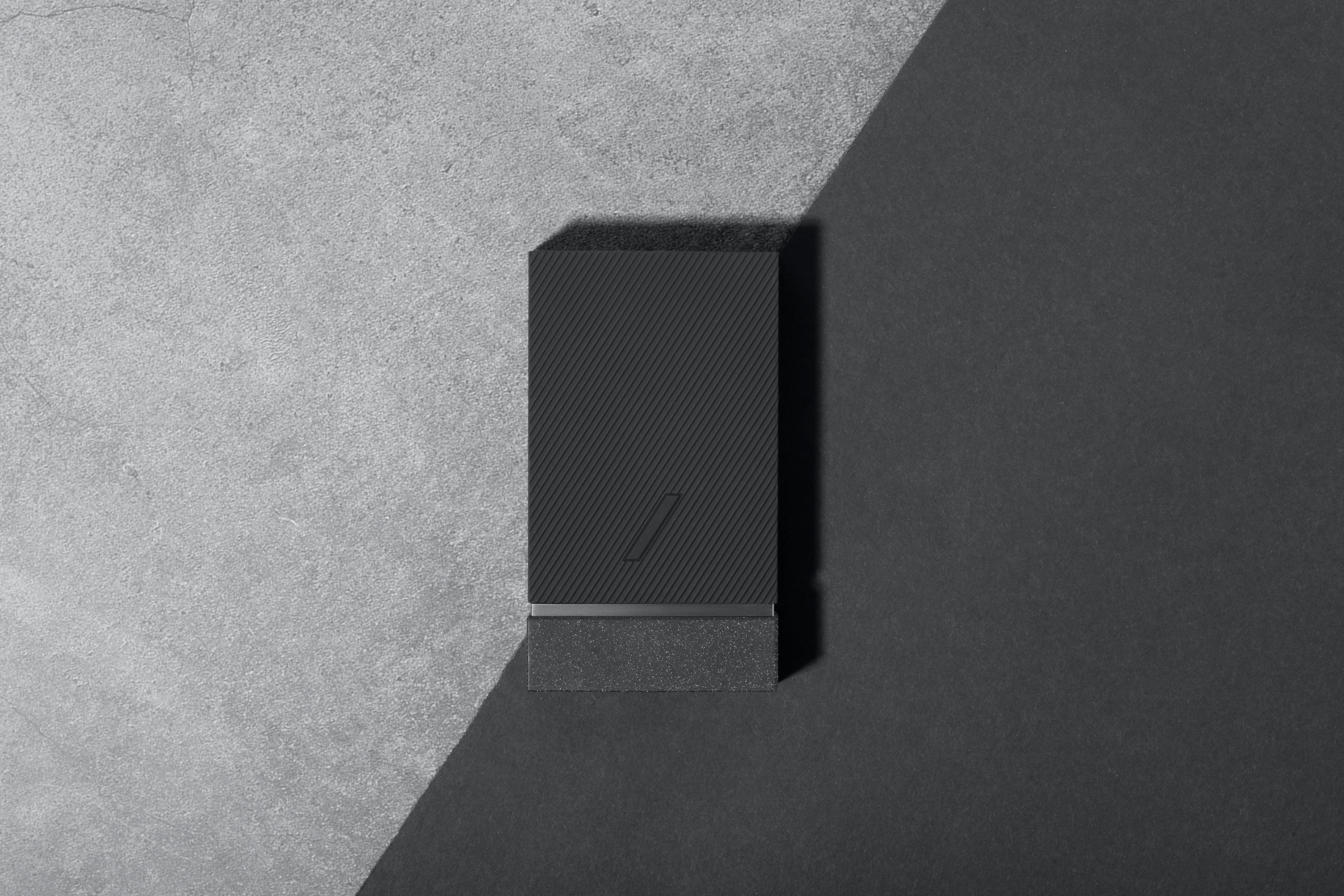 Power bank nero, strutturato su sfondo diviso diagonalmente grigio e nero.
