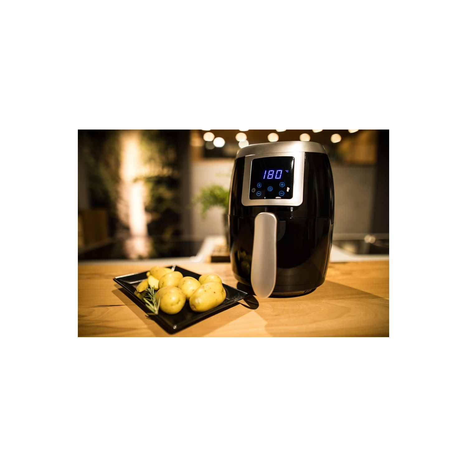 Freidora de aire negra con pantalla iluminada mostrando 180 grados. Bandeja de patatas al lado.