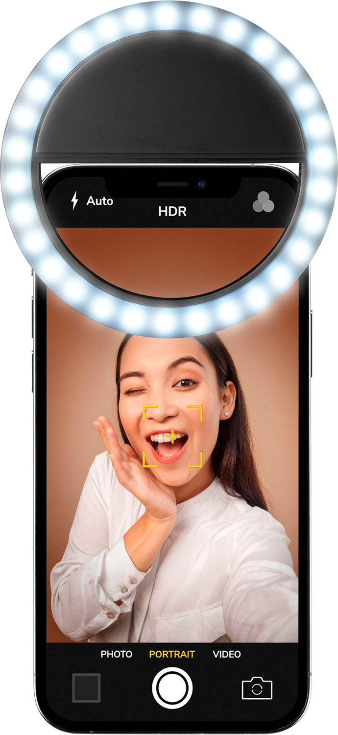 Une femme prend un selfie avec un téléphone et un anneau lumineux circulaire. Elle sourit et fait un clin d'œil.