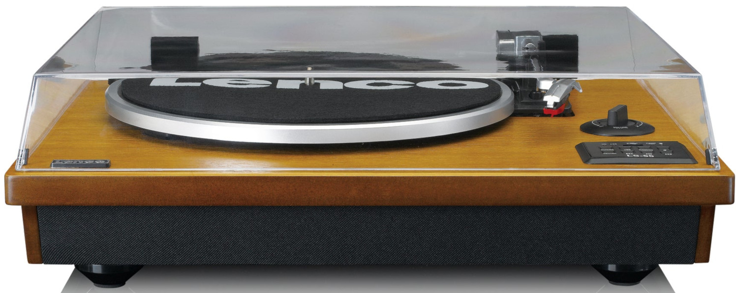 Une platine vinyle en bois avec un couvercle en plastique transparent. Détails incluent le bras, les commandes et la grille du haut-parleur.