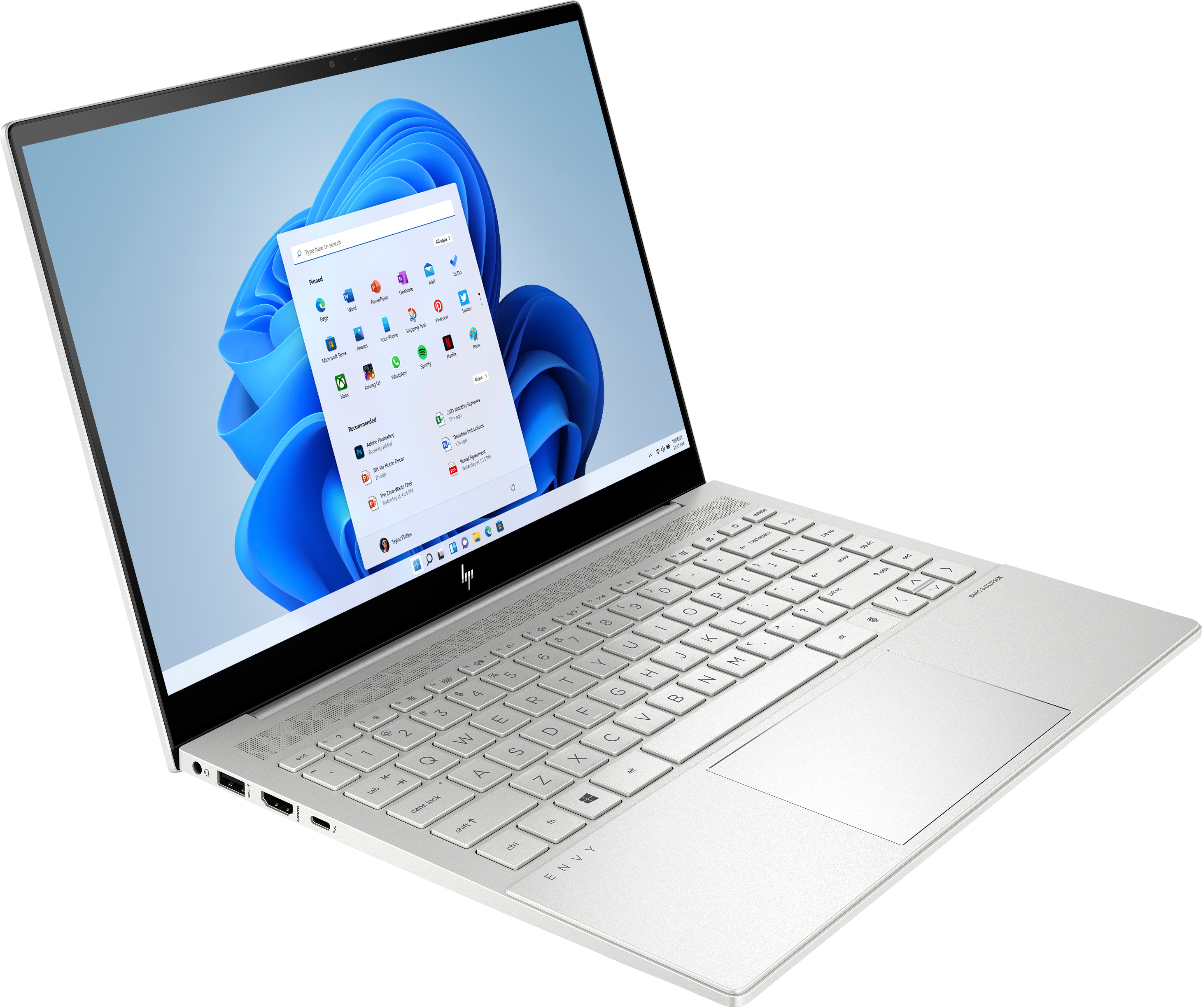 Portátil HP Envy plateado abierto, Windows 11 con iconos de aplicaciones.