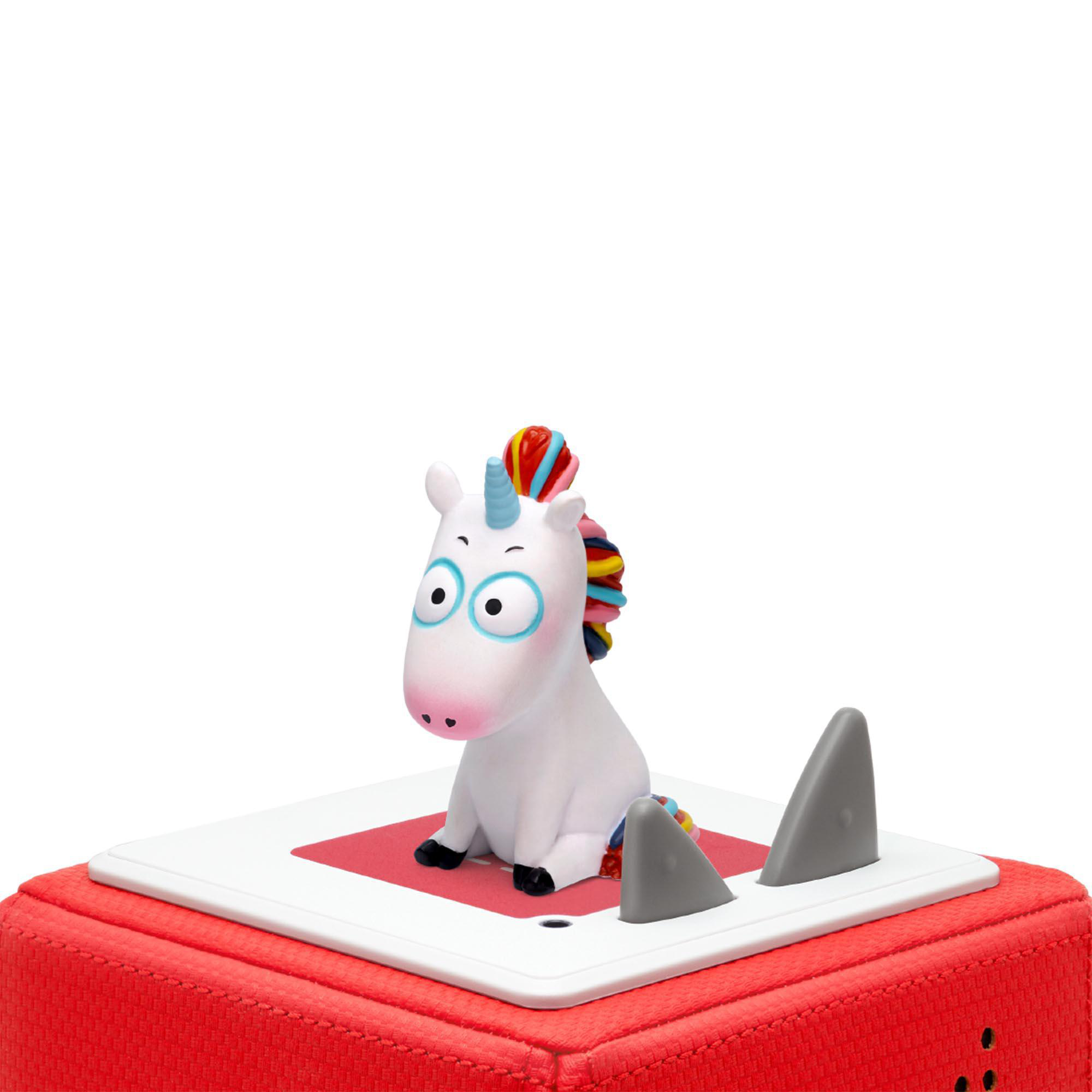 Ein Einhorn-Spielzeug sitzt auf roter Basis mit zwei Haifischflossen. Weißer Hintergrund.