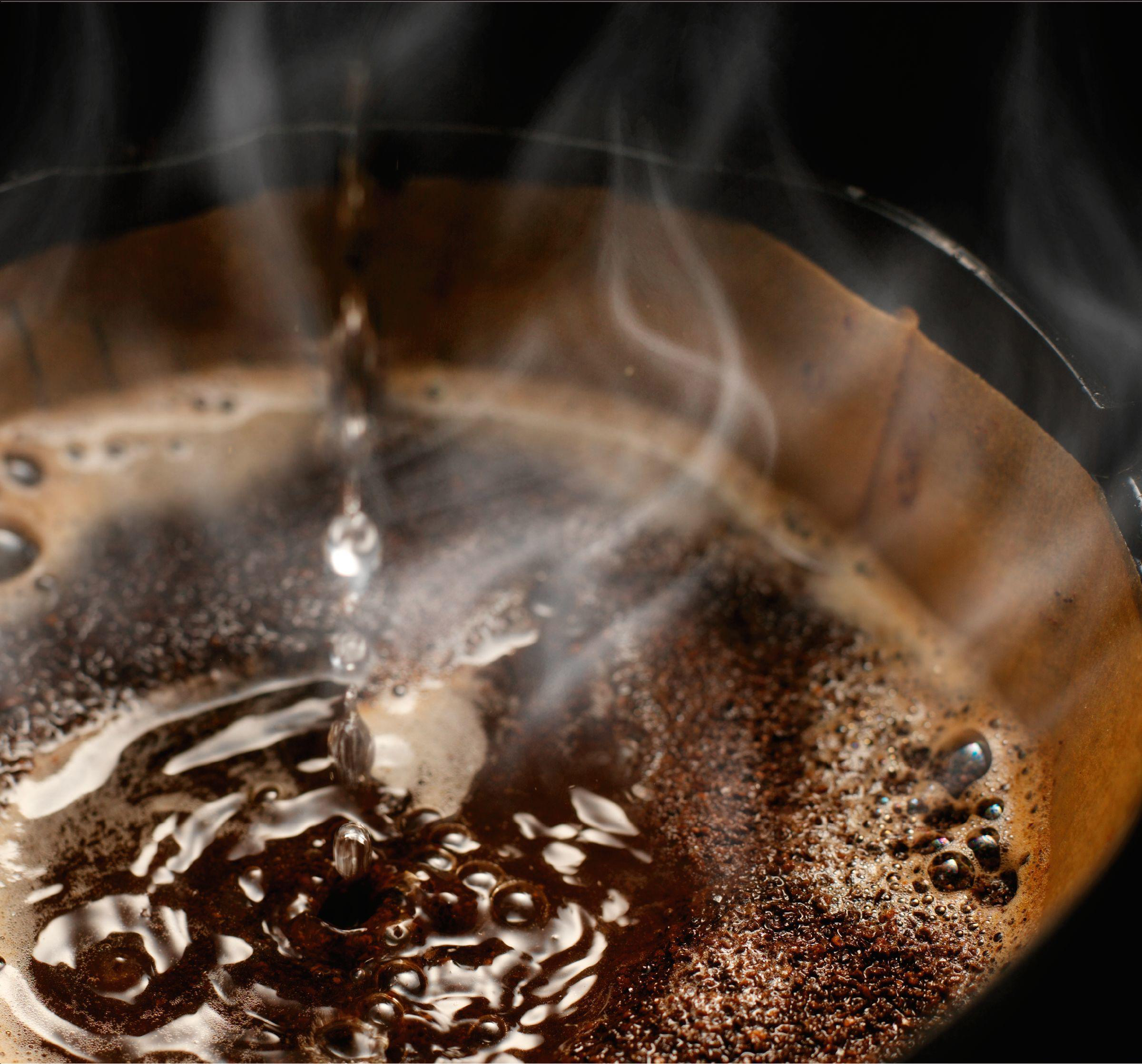 Nahaufnahme von Kaffeezubereitung mit Wassertropfen in Kaffeesatz.