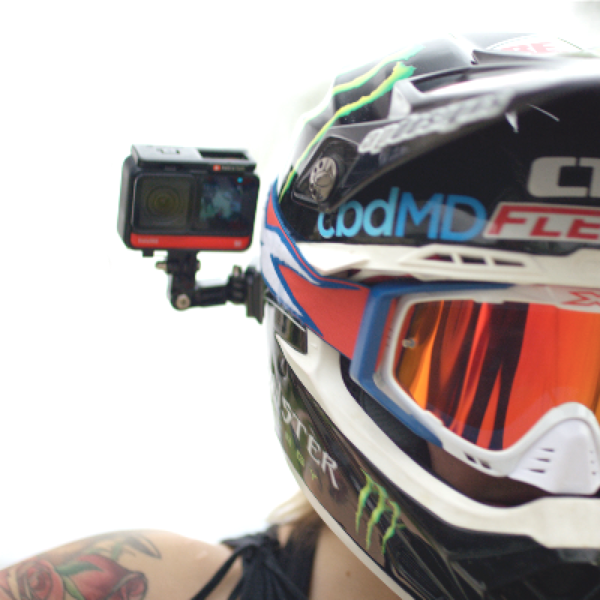 Helm mit Action-Kamera, eine Person mit Tattoo ist im Hintergrund sichtbar.