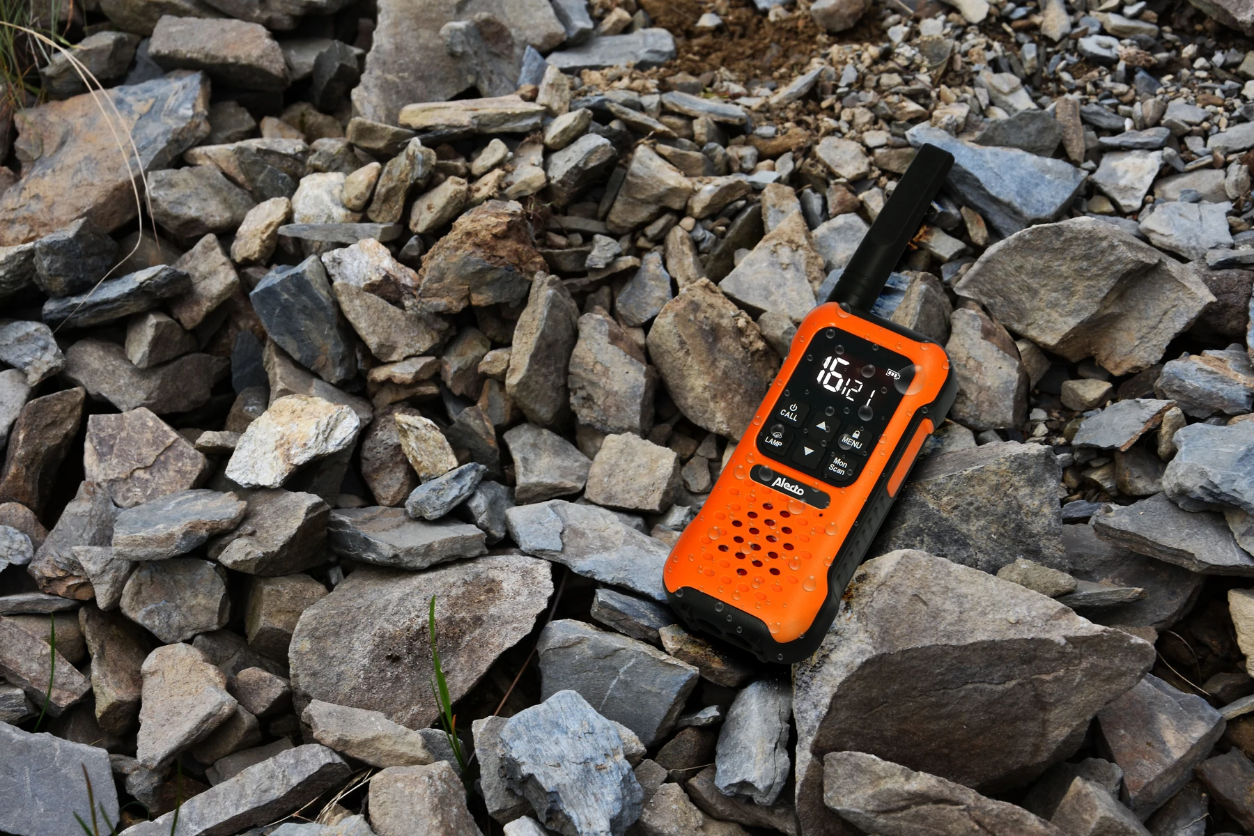 Oranges Walkie-Talkie auf einem Steinhaufen, mit Zeitanzeige.