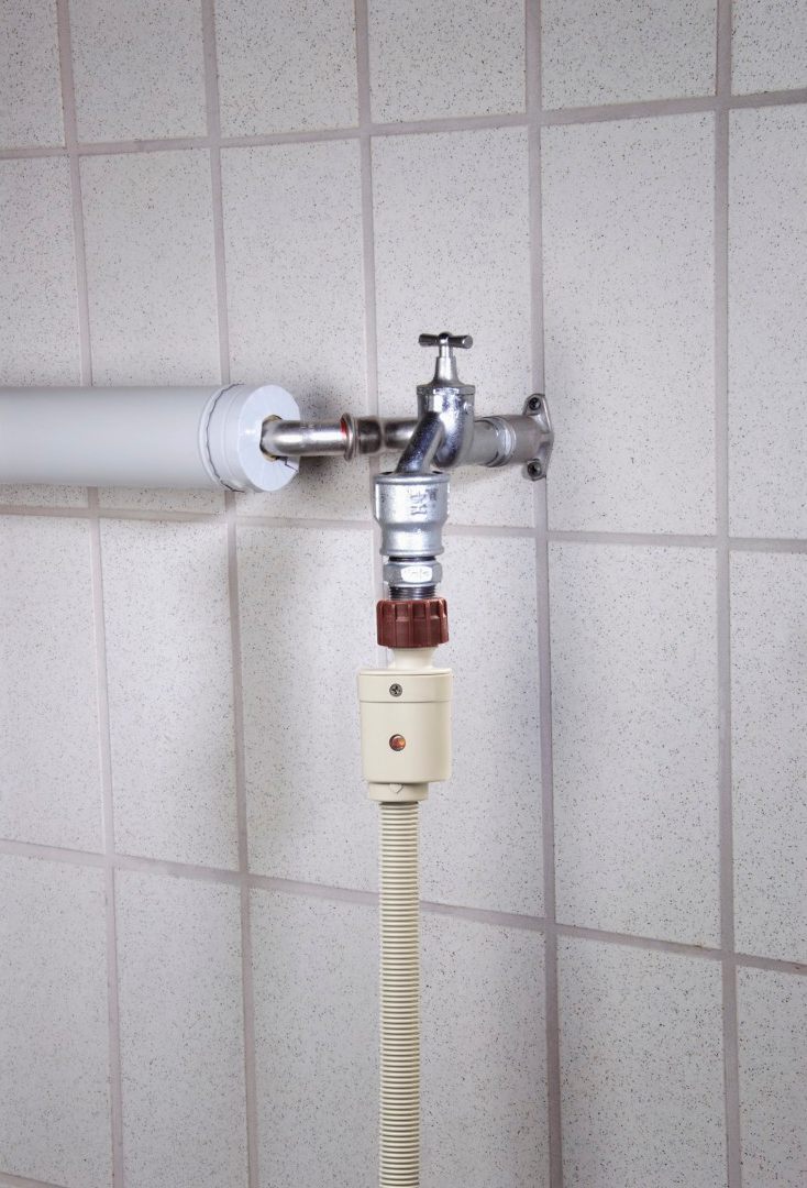 Rubinetto dell'acqua con attacco per tubo. Lo sfondo è una parete piastrellata.