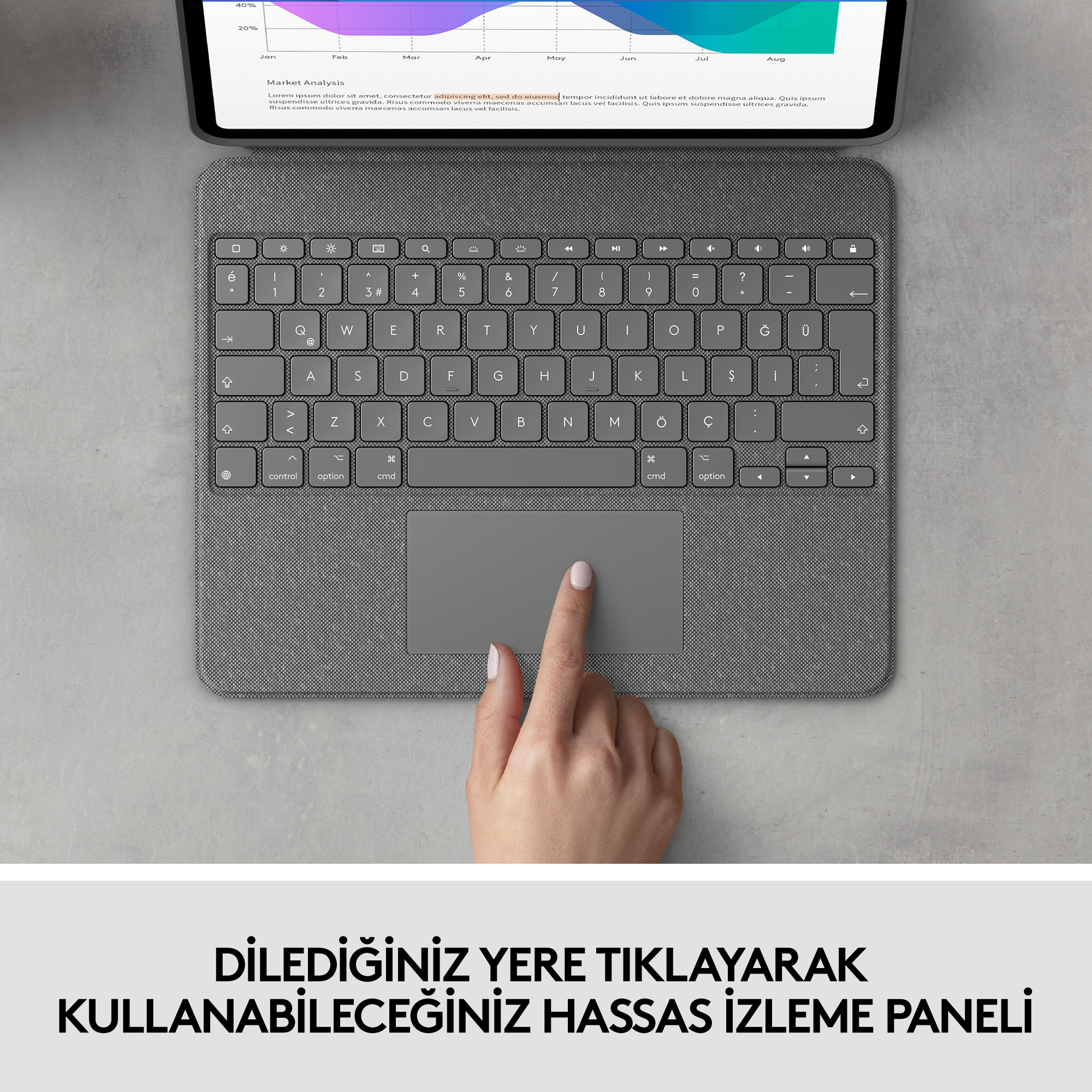 Bir el, bir klavyedeki gri bir dokunmatik yüzeye dokunuyor. Klavye, gri bir yüzey üzerindeki bir tablete bağlı.