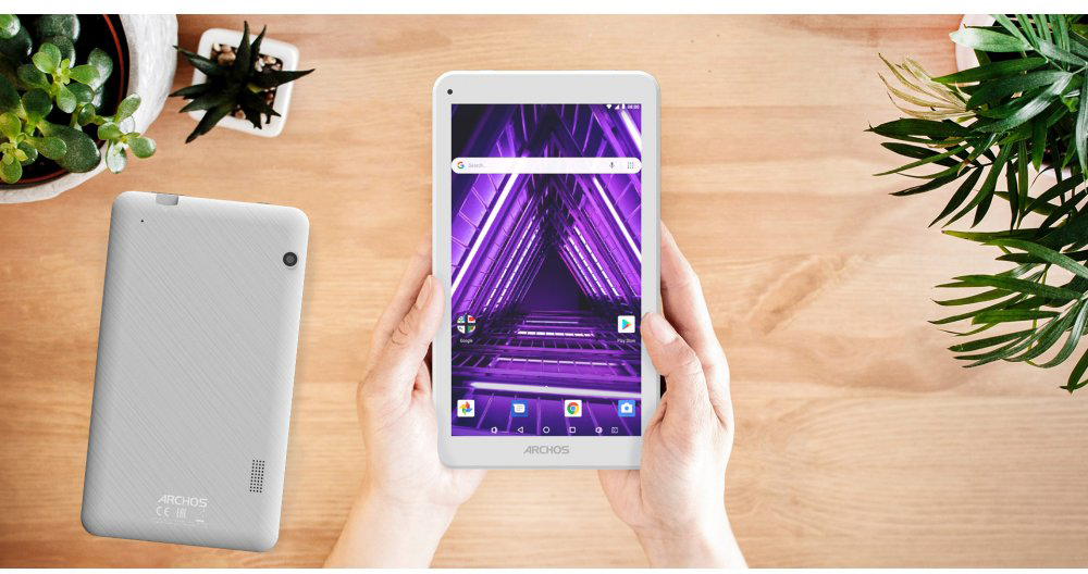 Tablette tenue par des mains, écran affiche design abstrait violet, sur table bois.