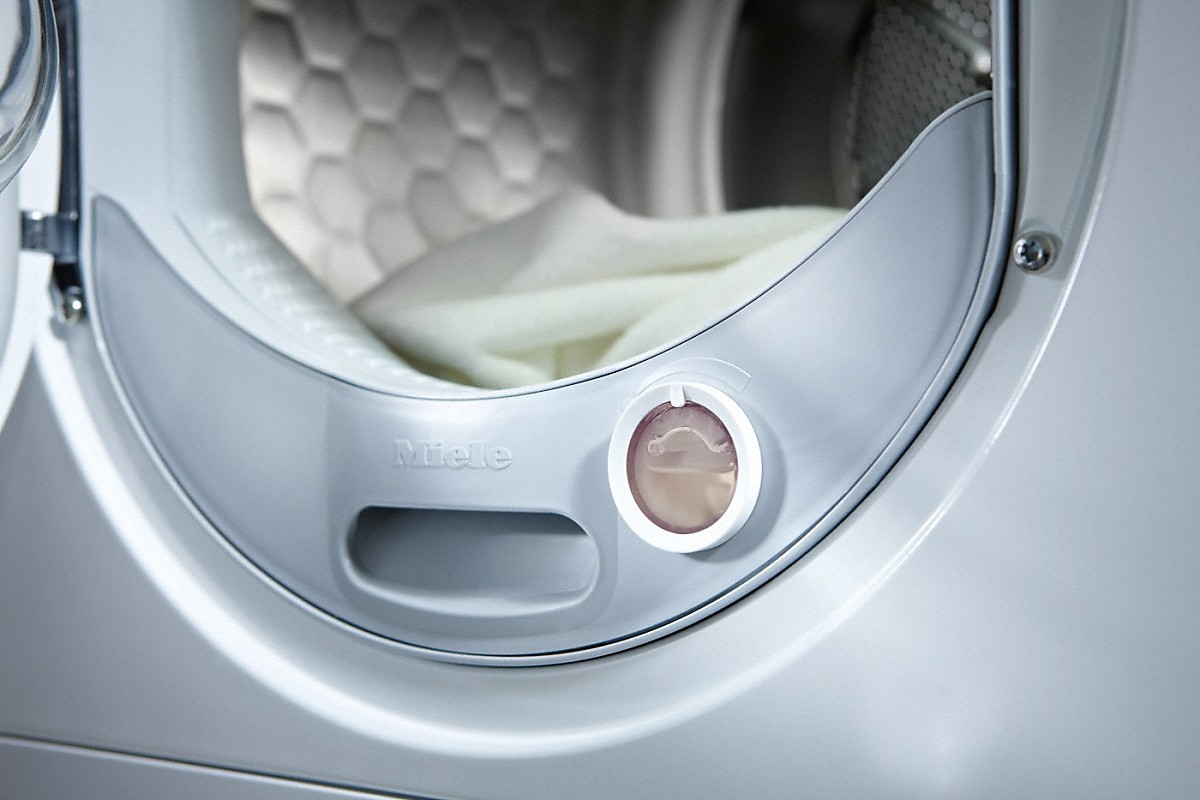 Close-up of a white washing machine door with a liquid dispenser.