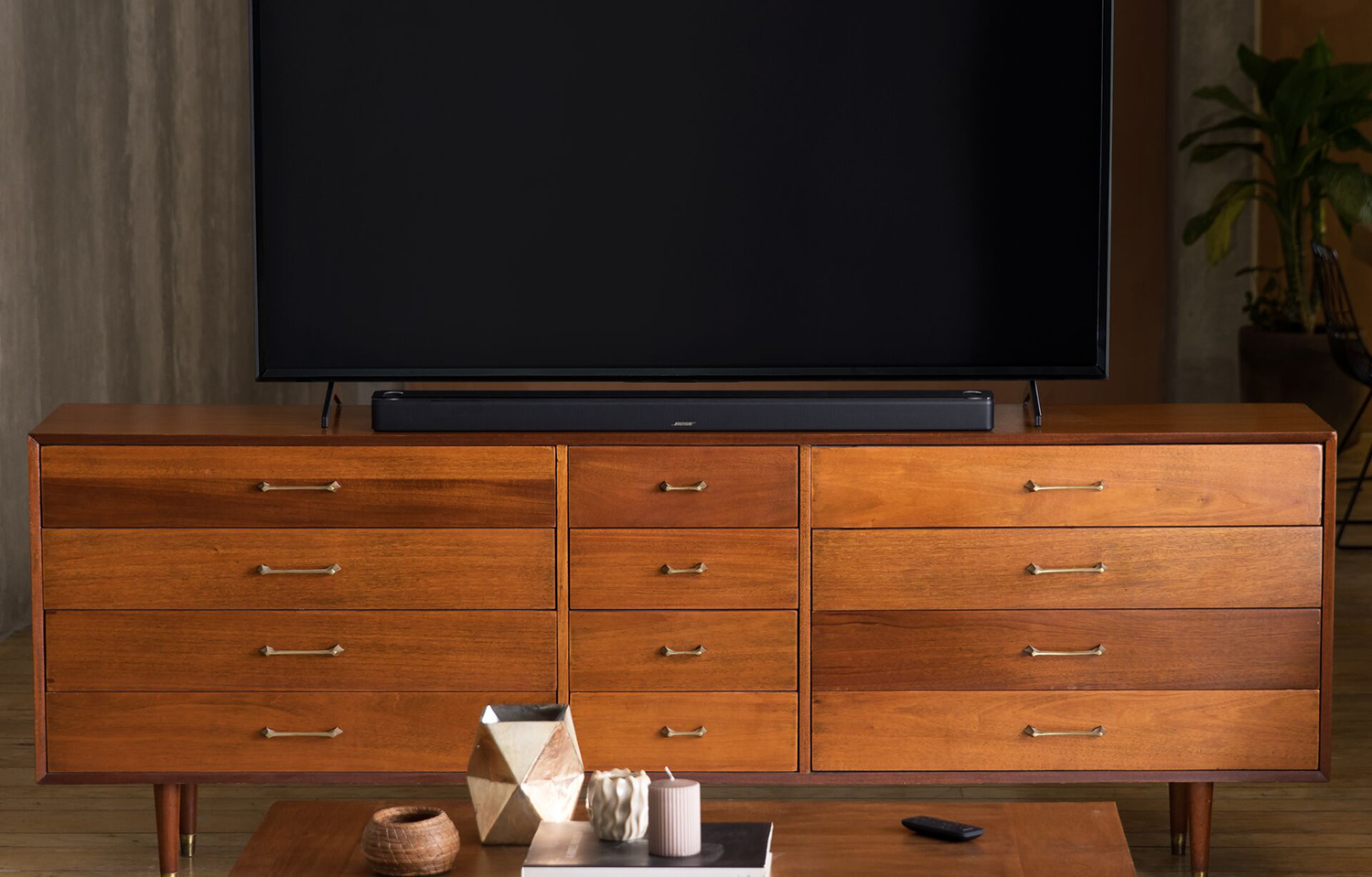 Een tv staat op een houten kast. Een soundbar staat onder de tv.