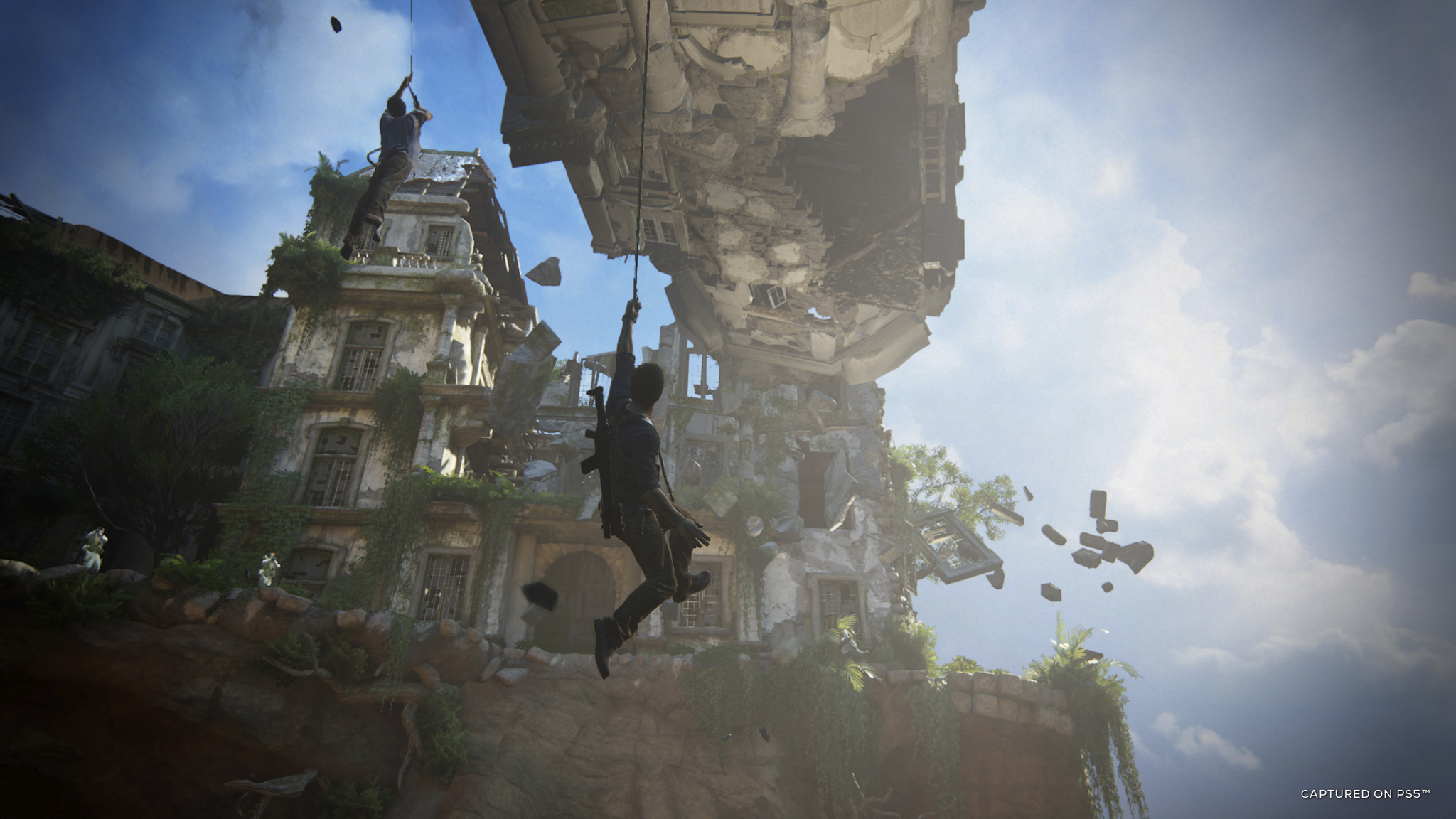 Man hanging from building, other man climbing above. Building is damaged and crumbling.