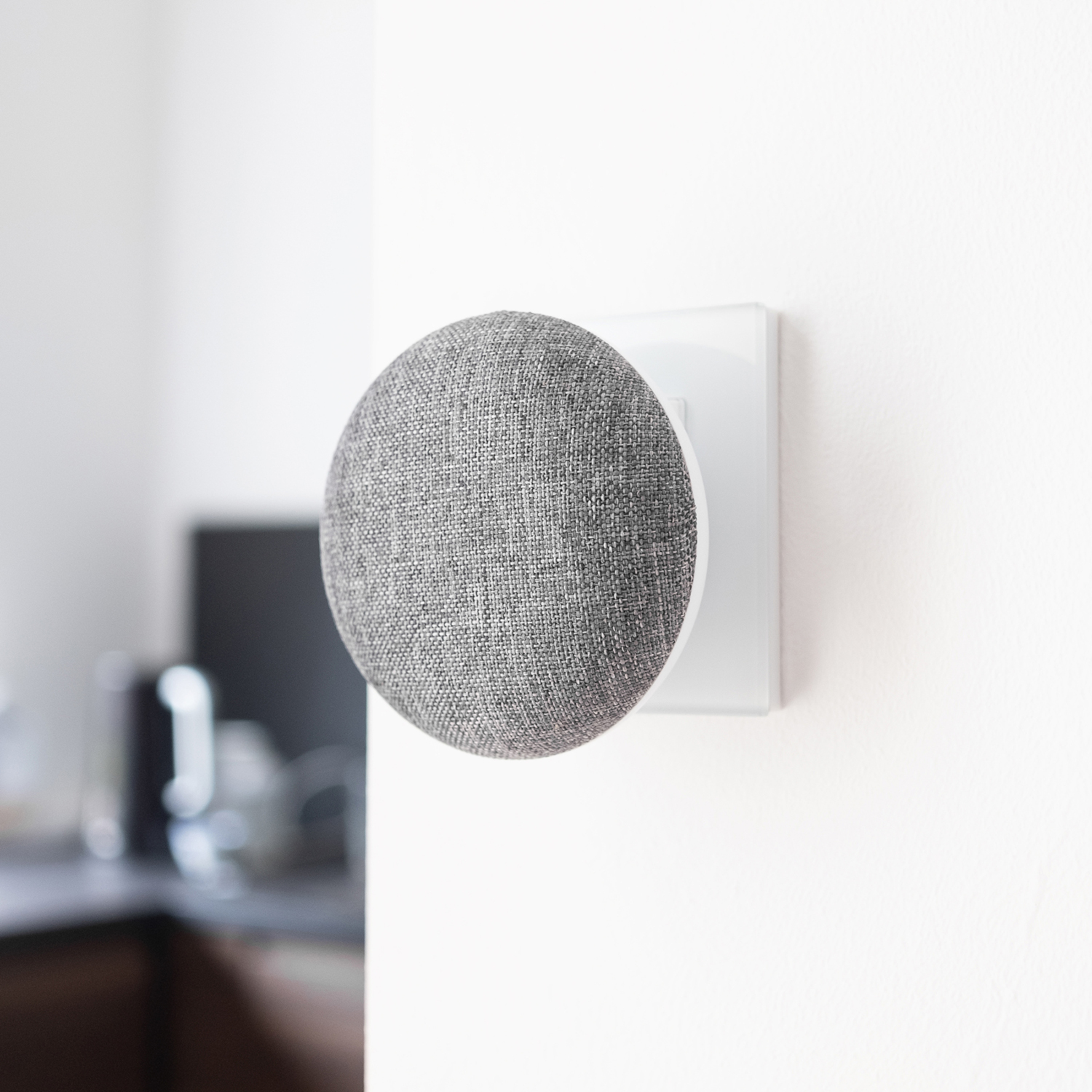 Google Nest Mini bevestigd aan een witte wand-stroomadapter.