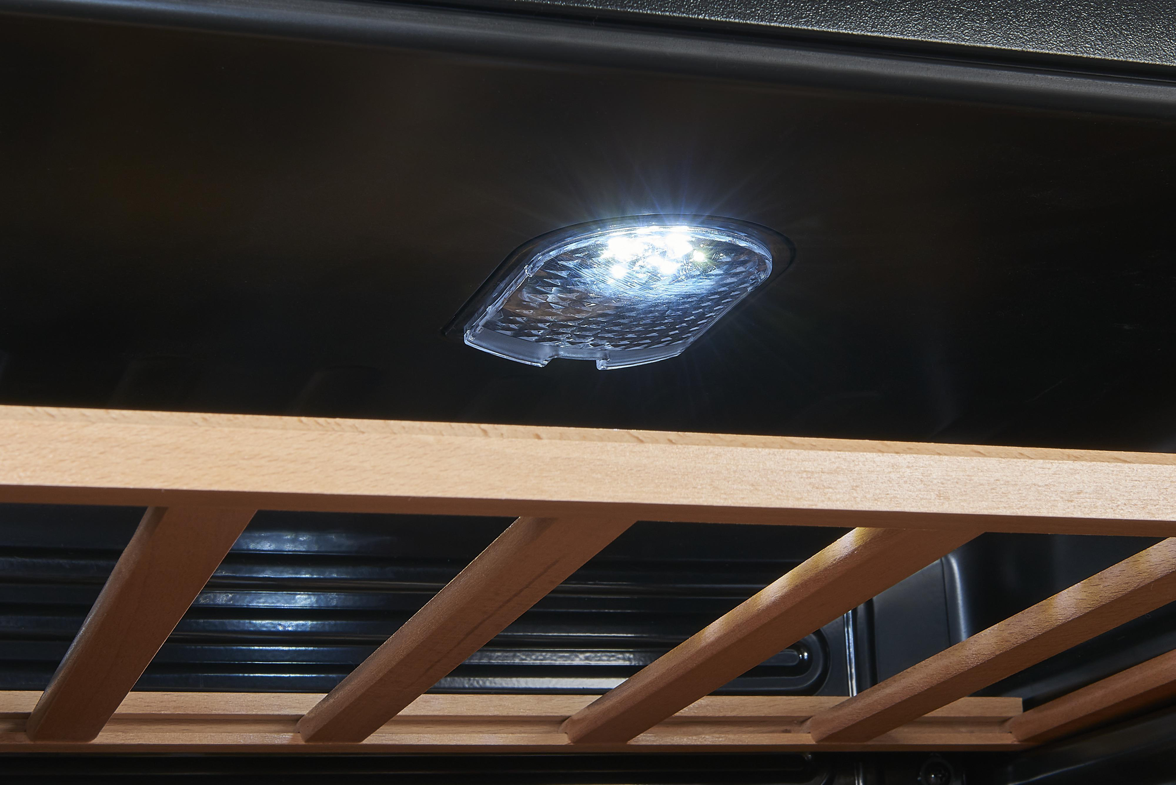 Nahaufnahme einer hellen LED-Leuchte im Weinkühler. Holzregal darunter.