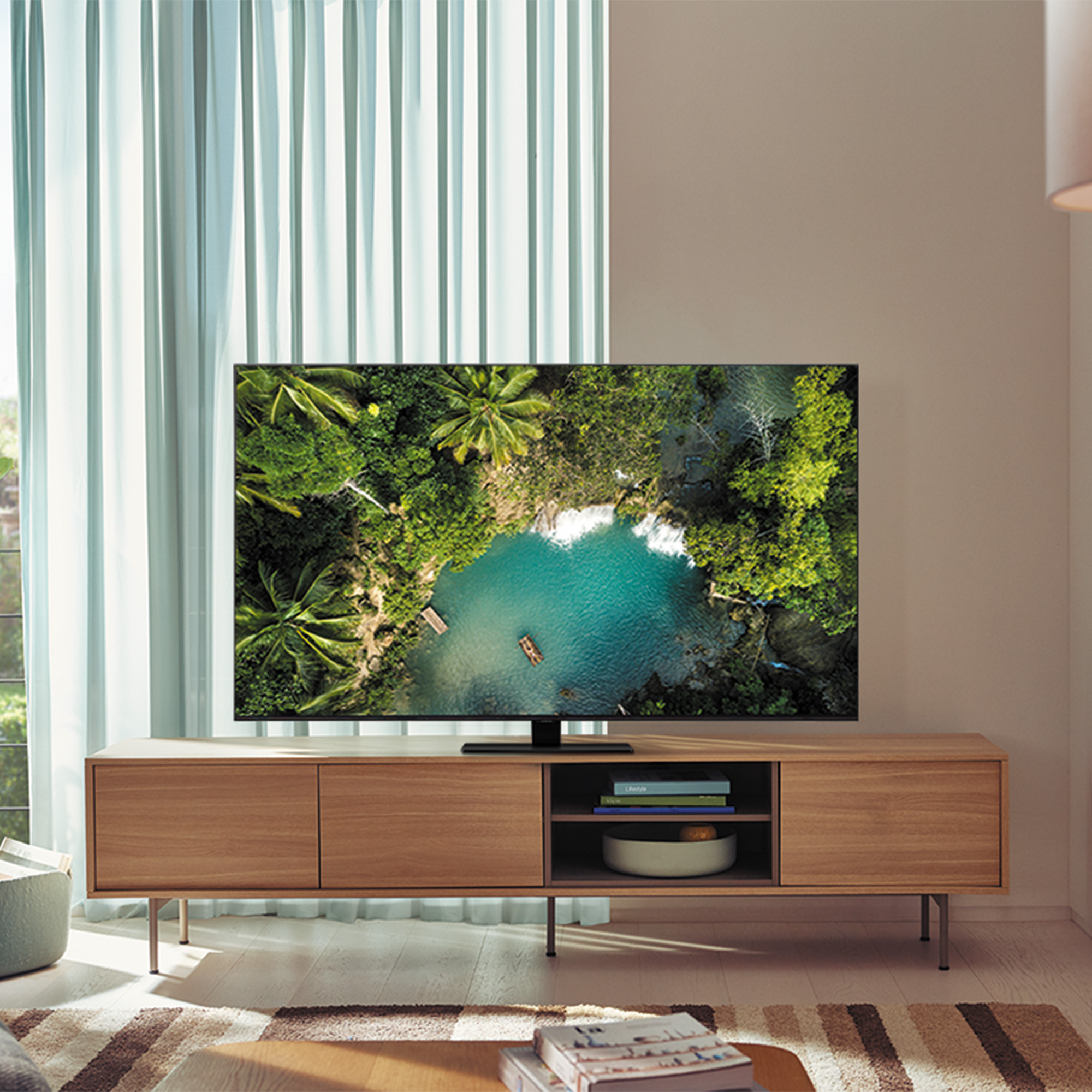 Televisor sobre un soporte de madera. Muestra una vista aérea de un lago y árboles.