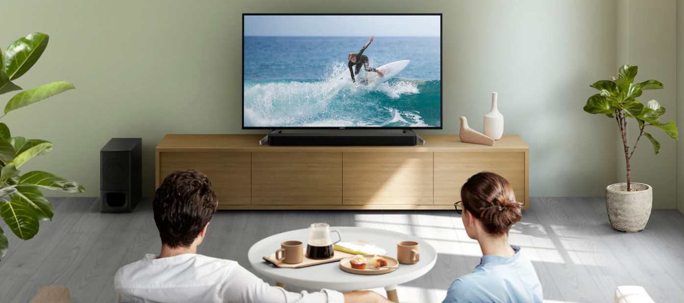 TV, soundbar ve TV'de sörf izleyen bir çift ile oturma odası kurulumu.