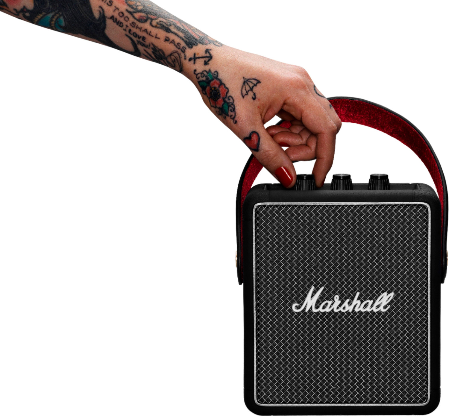 Une main tatouée ajuste le bouton de volume d'un haut-parleur Marshall noir.