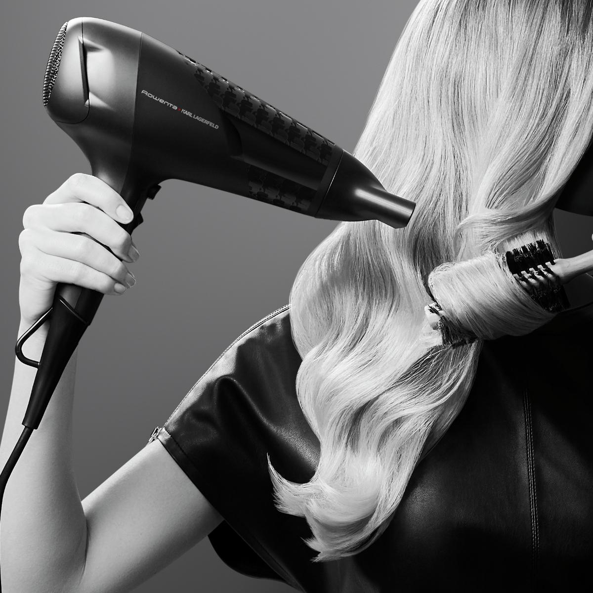 Eine Person, die einen Haartrockner und eine Bürste auf blondem Haar verwendet.