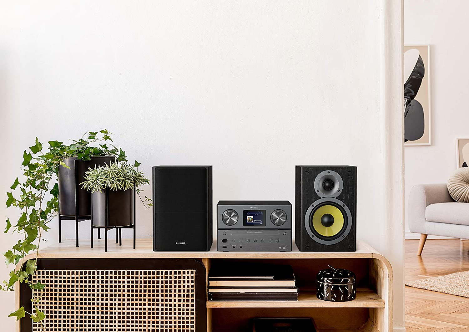 A modern living room setup with stereo speakers, a media player, and plants on a wooden cabinet.