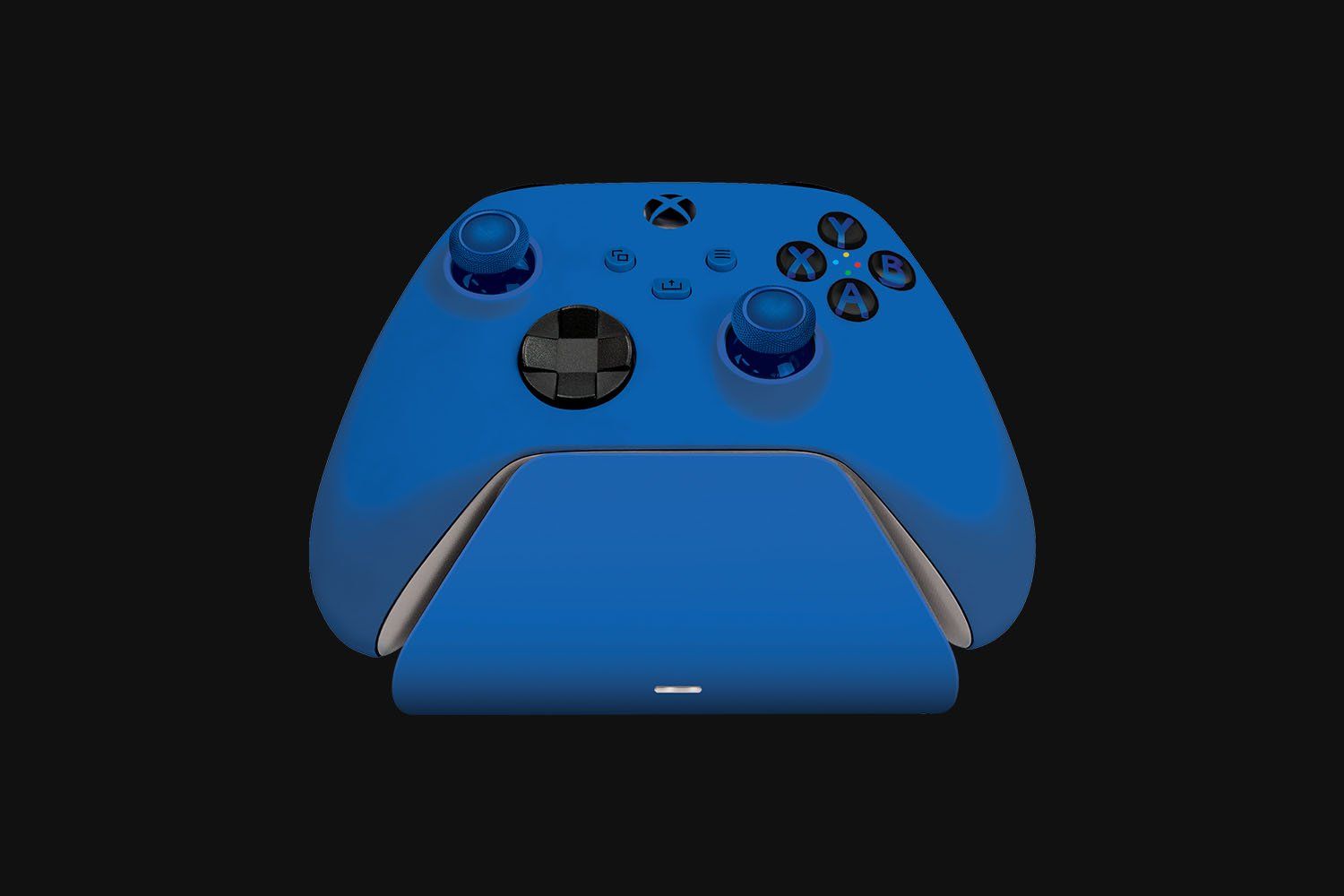A blue Xbox controller on a charging base, against a dark background.