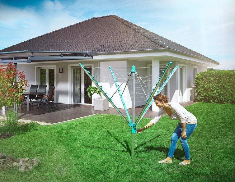 Frau, die eine teal-farbene Wäschespinne im Garten einstellt.