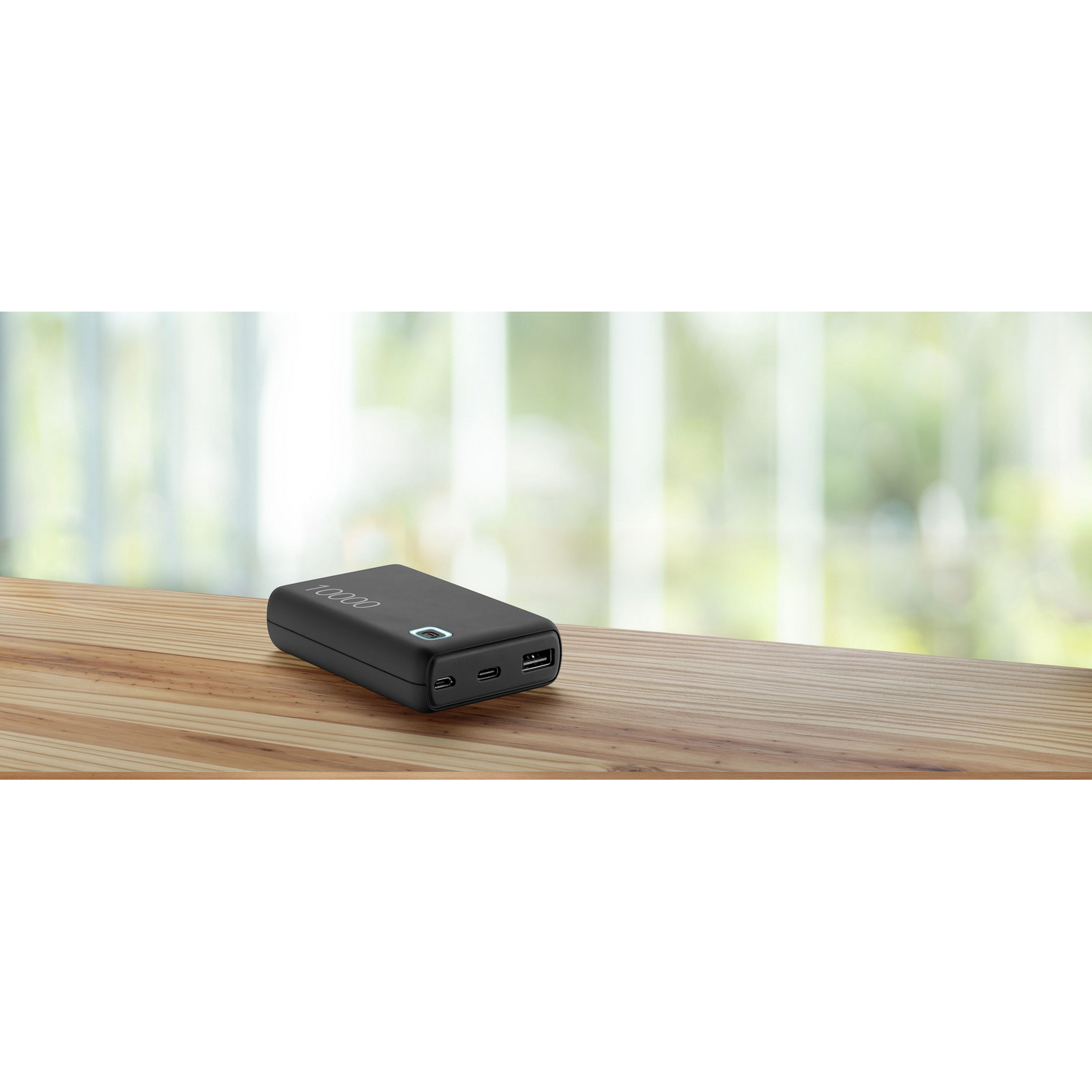 Un banco de energía negro sobre una mesa de madera, con un fondo de ventana borroso.