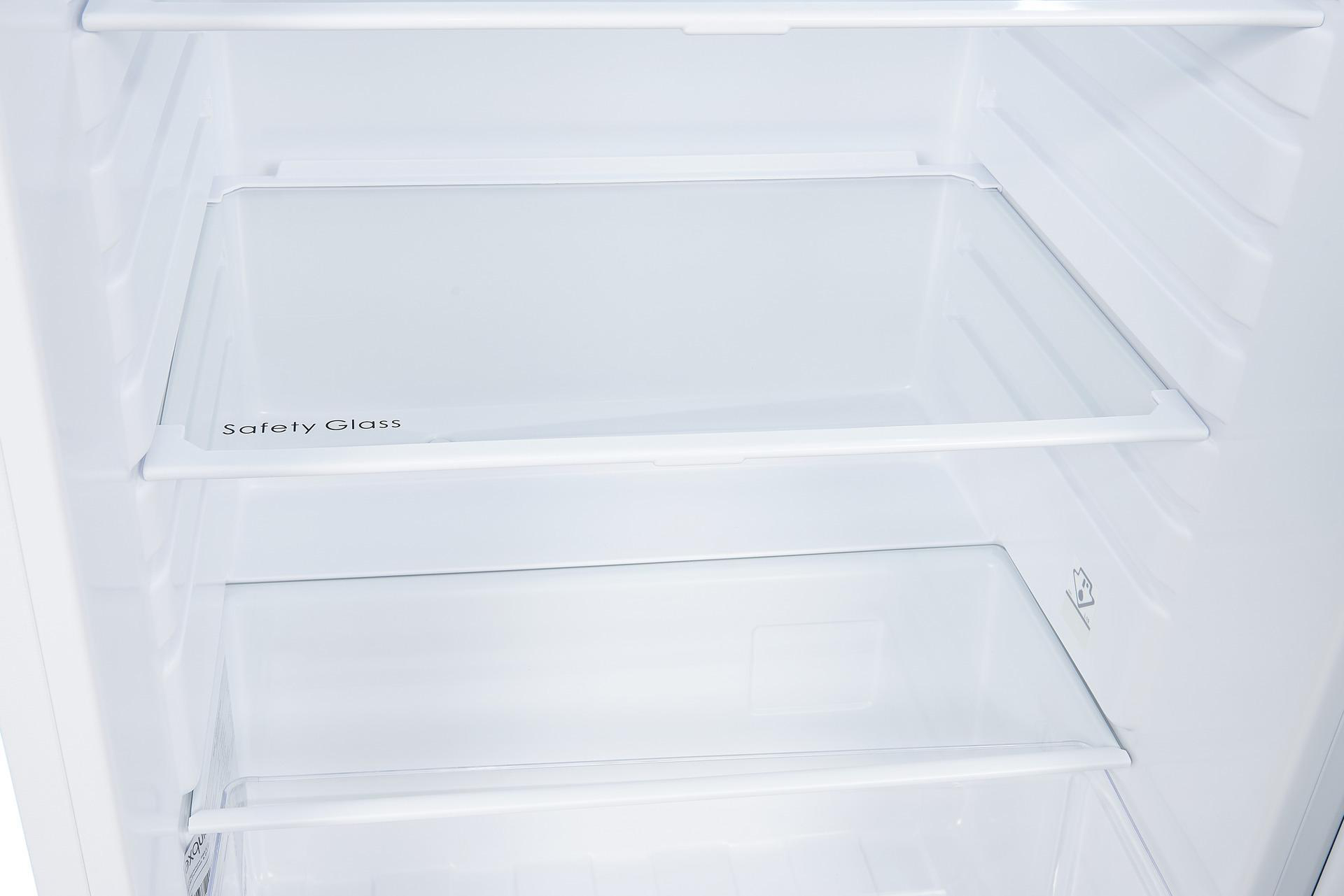 Ein leerer Kühlschrankinnenraum mit Glasböden. Die Regale sind mit Sicherheitsglas beschriftet.
