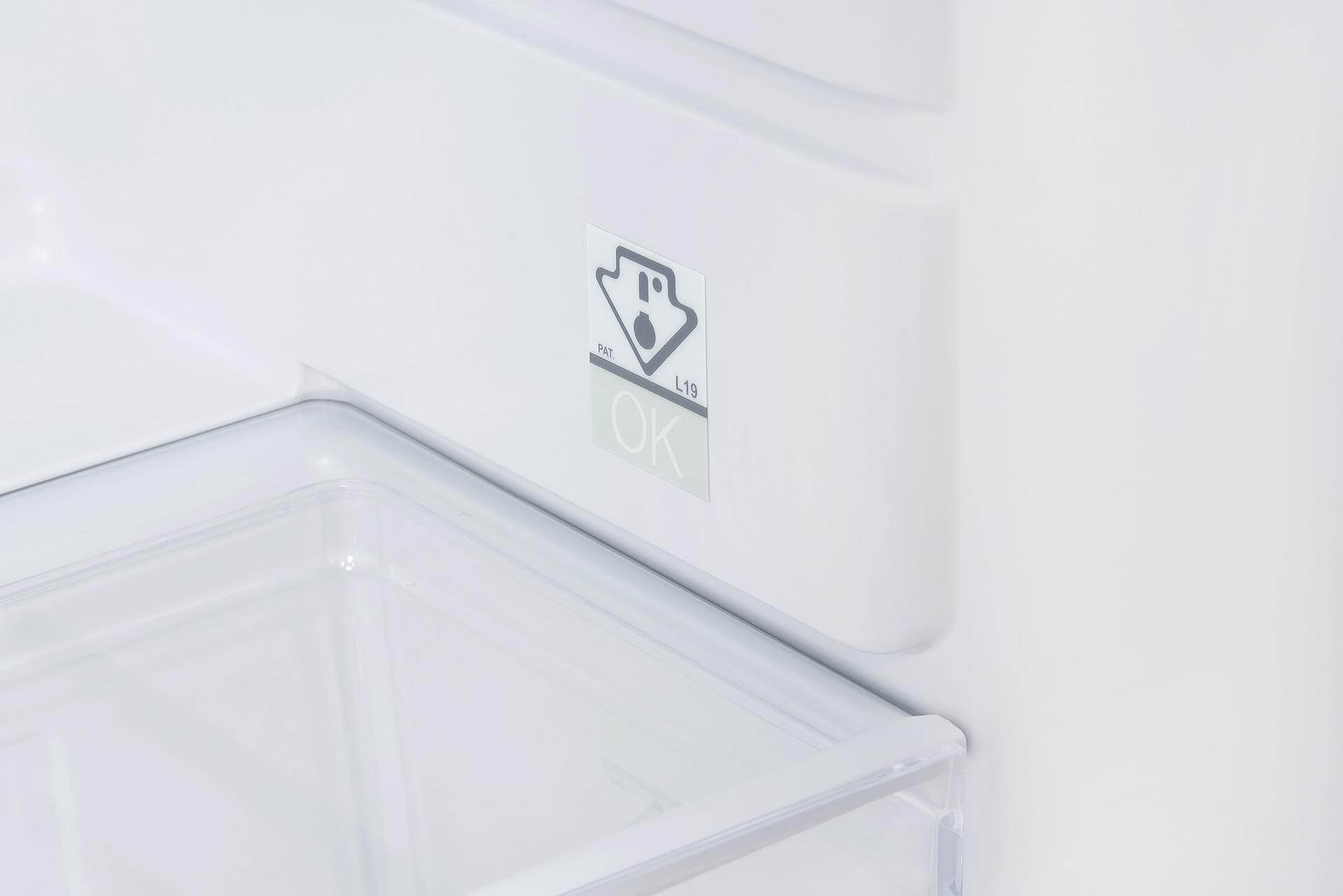 Detail des Kühlschrankinnenraums mit einem OK-Aufkleber.