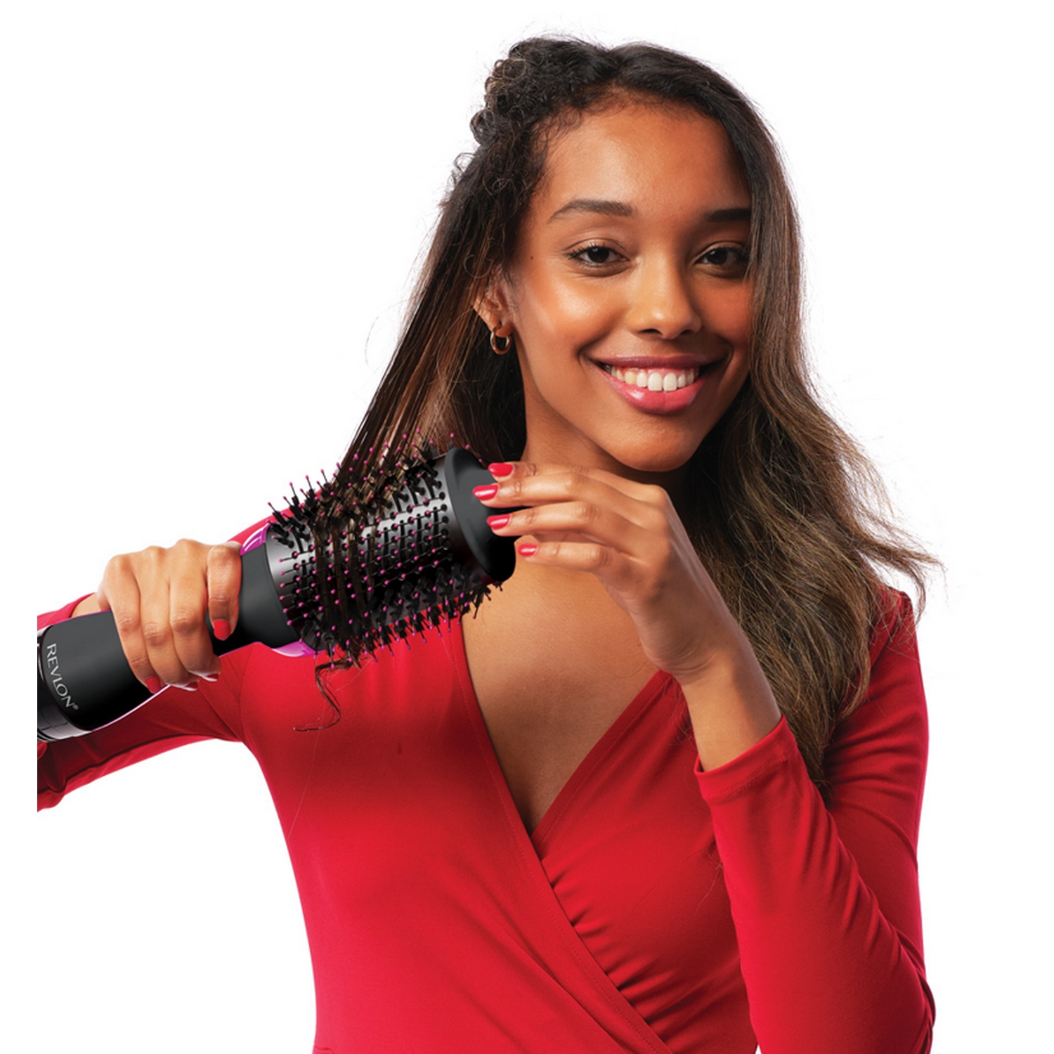 Mujer usando un cepillo secador de pelo Revlon negro y rosa, peinando su cabello. Sonríe a la cámara.