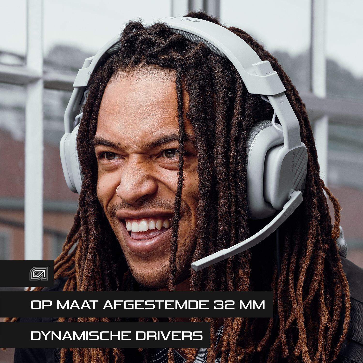 Man met grijze koptelefoon met microfoon, lachend, dreadlocks.