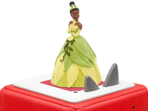 Prinzessin Tiana Figur im grünen Kleid, auf roter Box mit grauen Haifischflossen. Weißer Hintergrund.