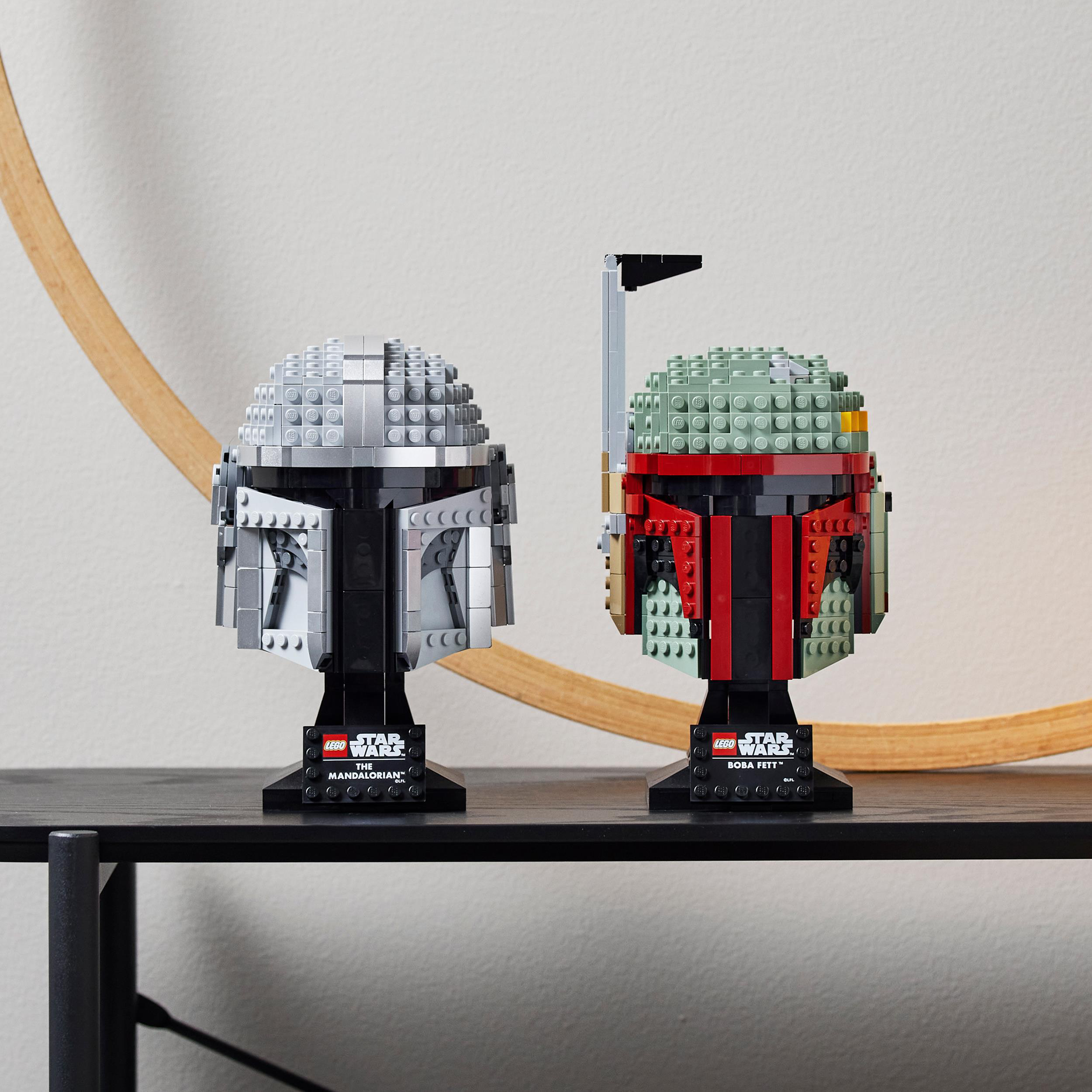 Zwei Lego Star Wars Helme: ein silberner Mandalorianer, ein grüner und roter Boba Fett.