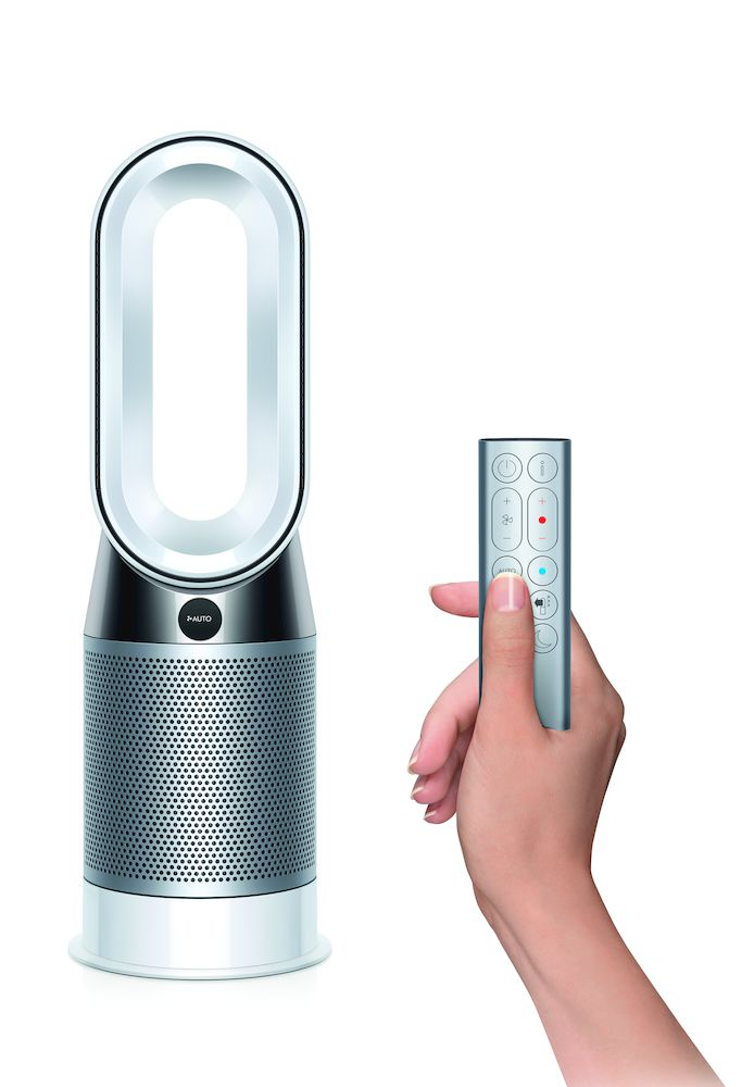 Ventilador blanco y plateado con mando. Una mano sostiene el mando.