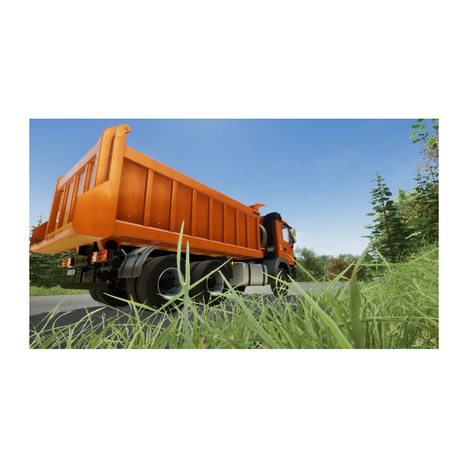 Un camión volquete naranja conduciendo en una carretera con hierba verde y cielo azul.