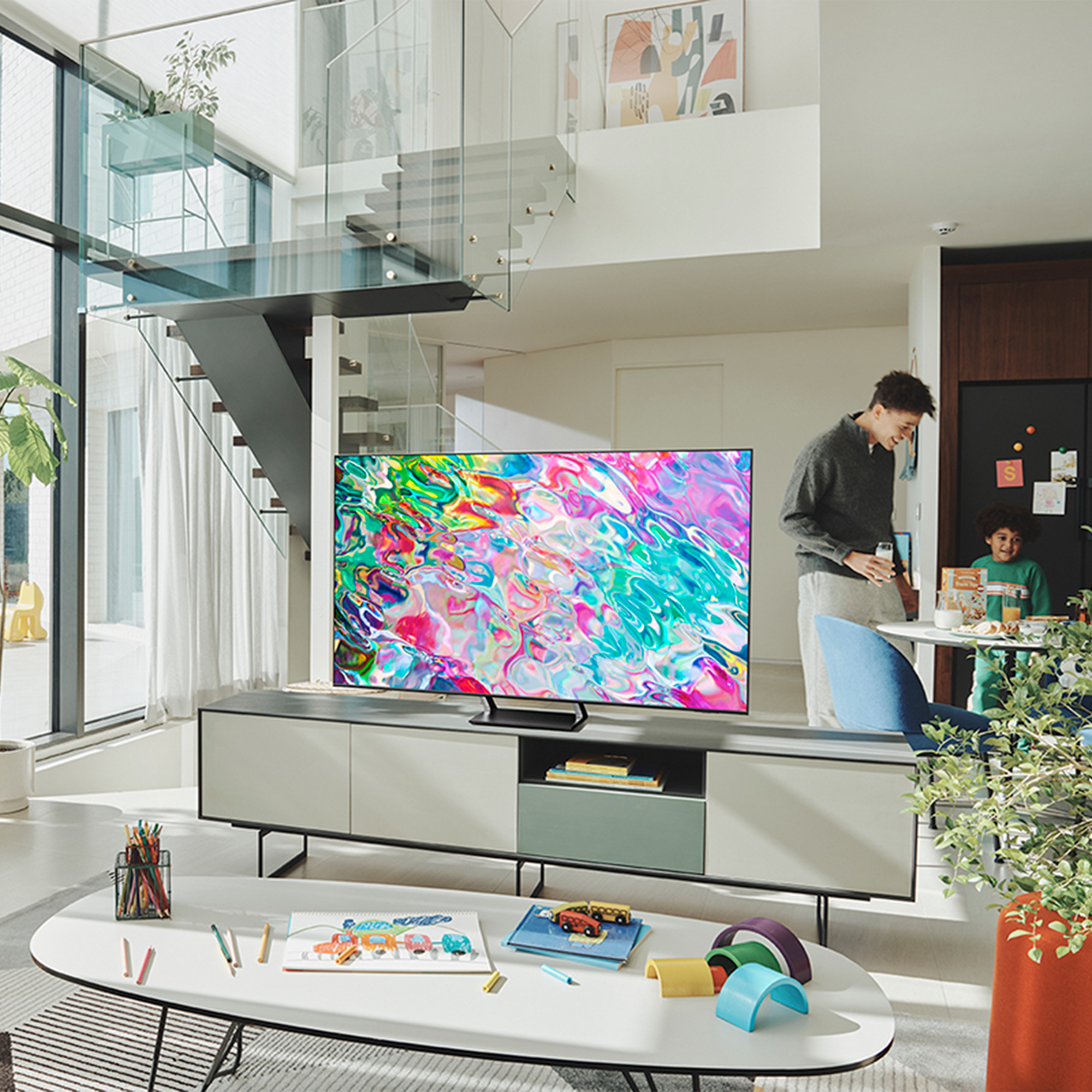 Salón con TV mostrando gráficos coloridos. Un hombre y un niño en el fondo.