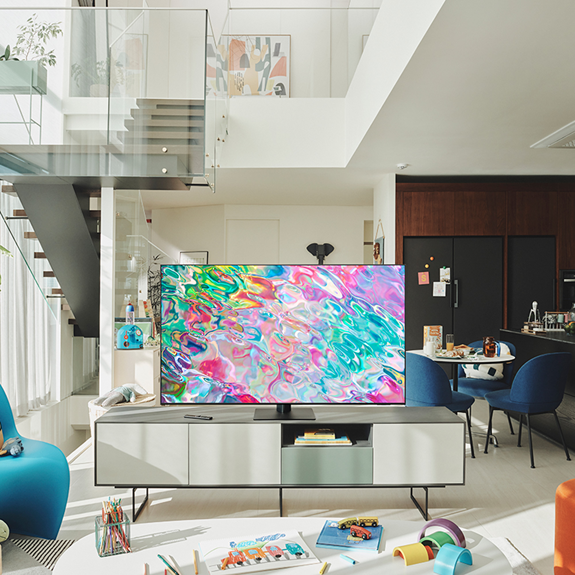 Salón con un televisor grande en un mueble y una escalera al fondo. Diseño interior moderno.