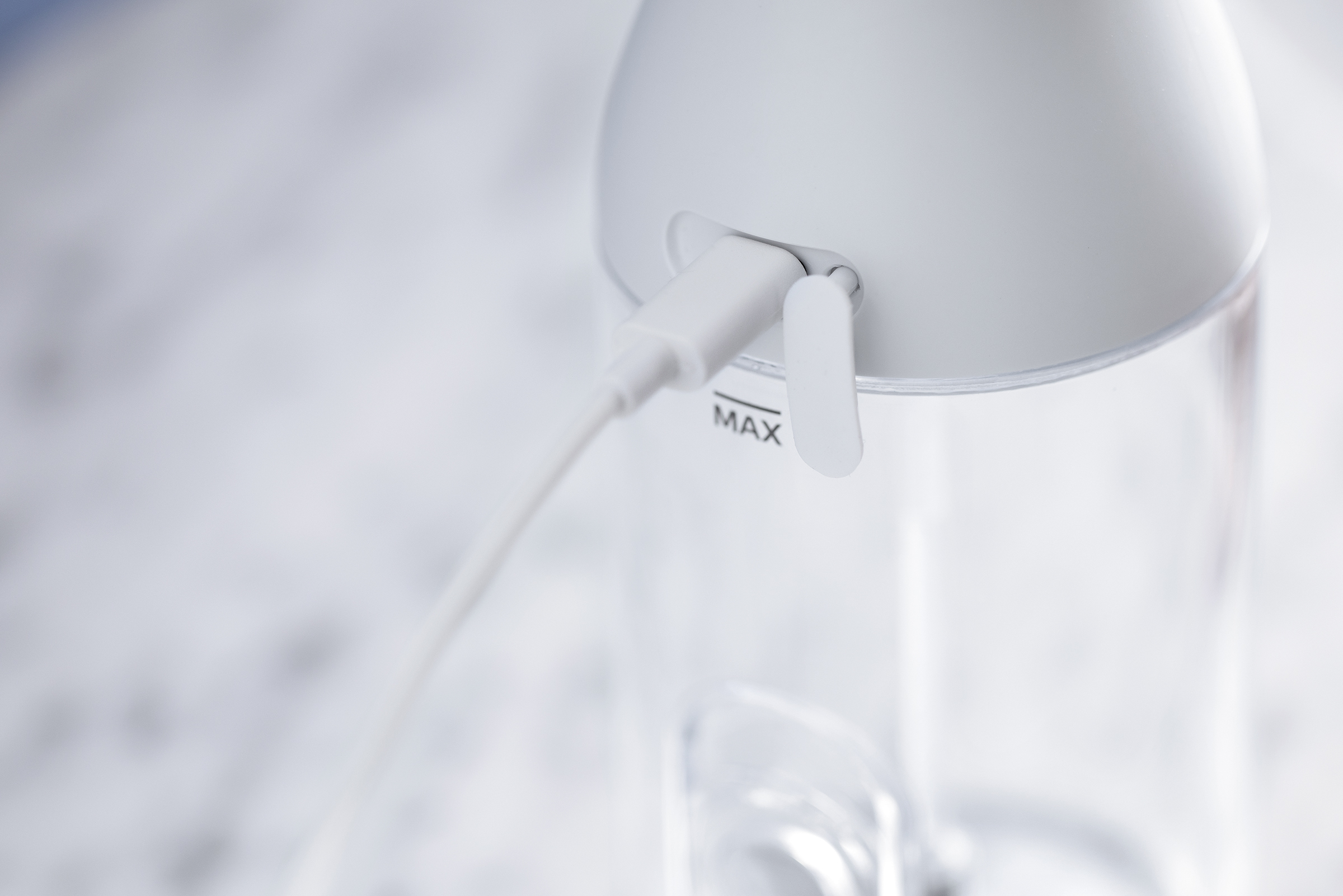 Gros plan sur une bouteille d'eau blanche avec un câble USB blanc branché.